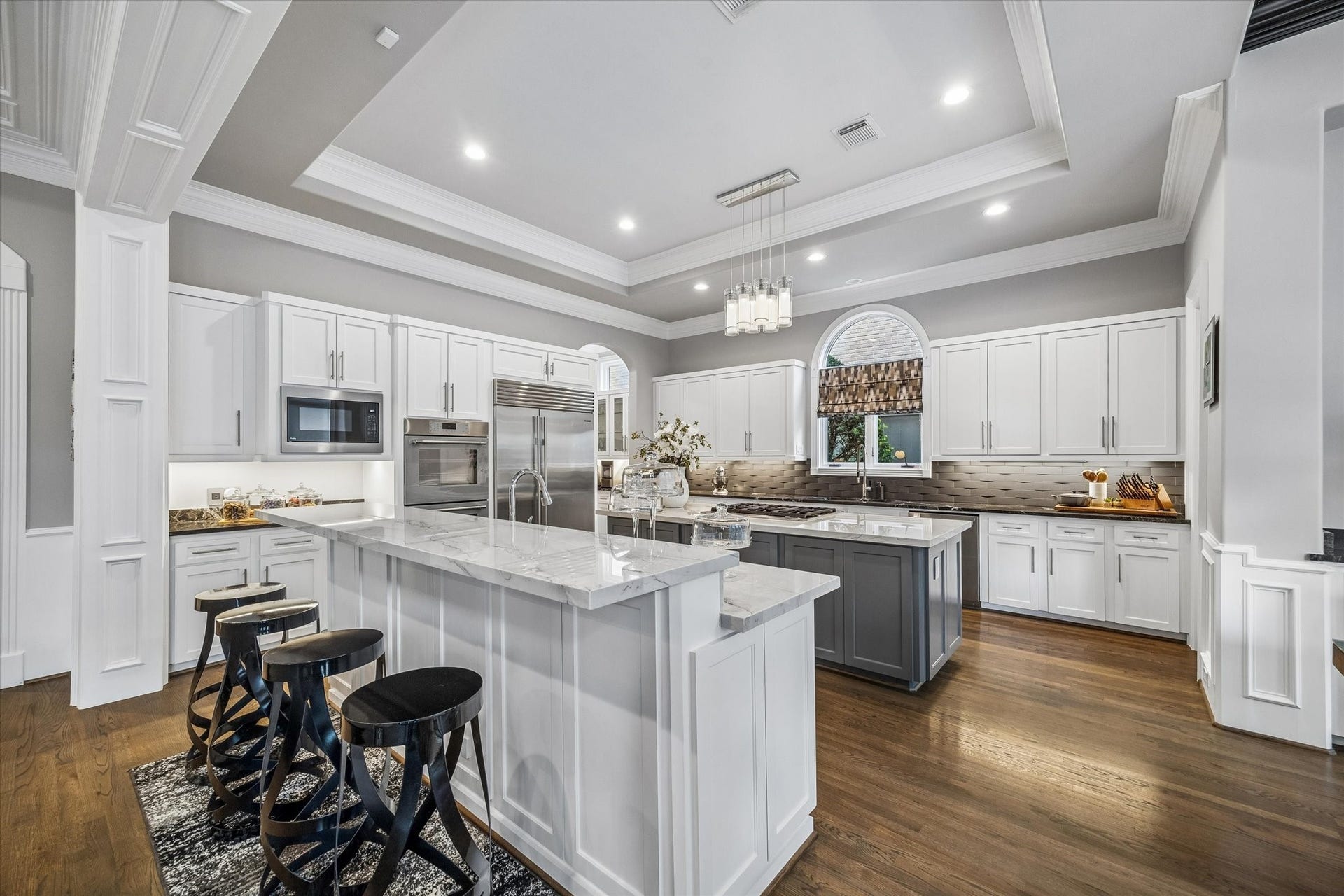 Recently renovated kitchen features double islands with Le Blanc quartzite countertops, creating the perfect gathering space.
