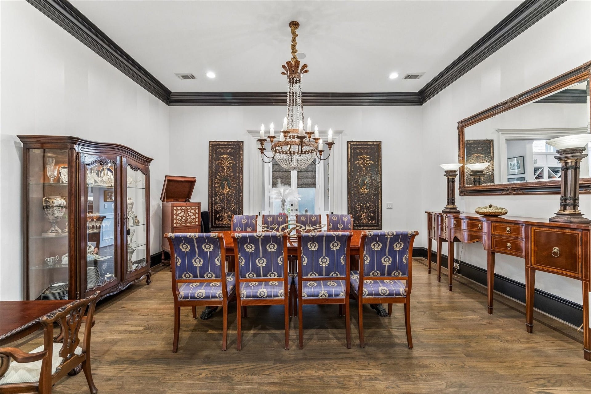 Elegant formal dining room with detailed crown molding, a statement chandelier, and ample space for a large dining table. Doors at the back of the room provide convenient access to the Butler's Pantry.