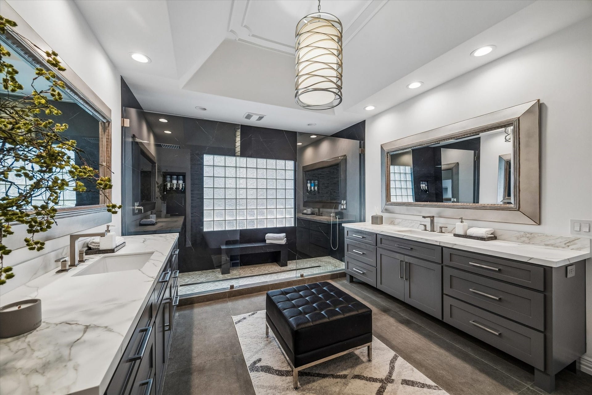 Spa-like primary bathroom with dual vanities, custom cabinetry, and an expansive glass enclosed shower.