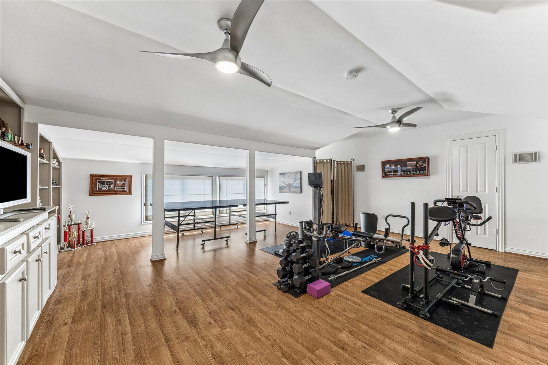 Spacious third floor flex space with built-in shelving and storage, currently used as a workout room.