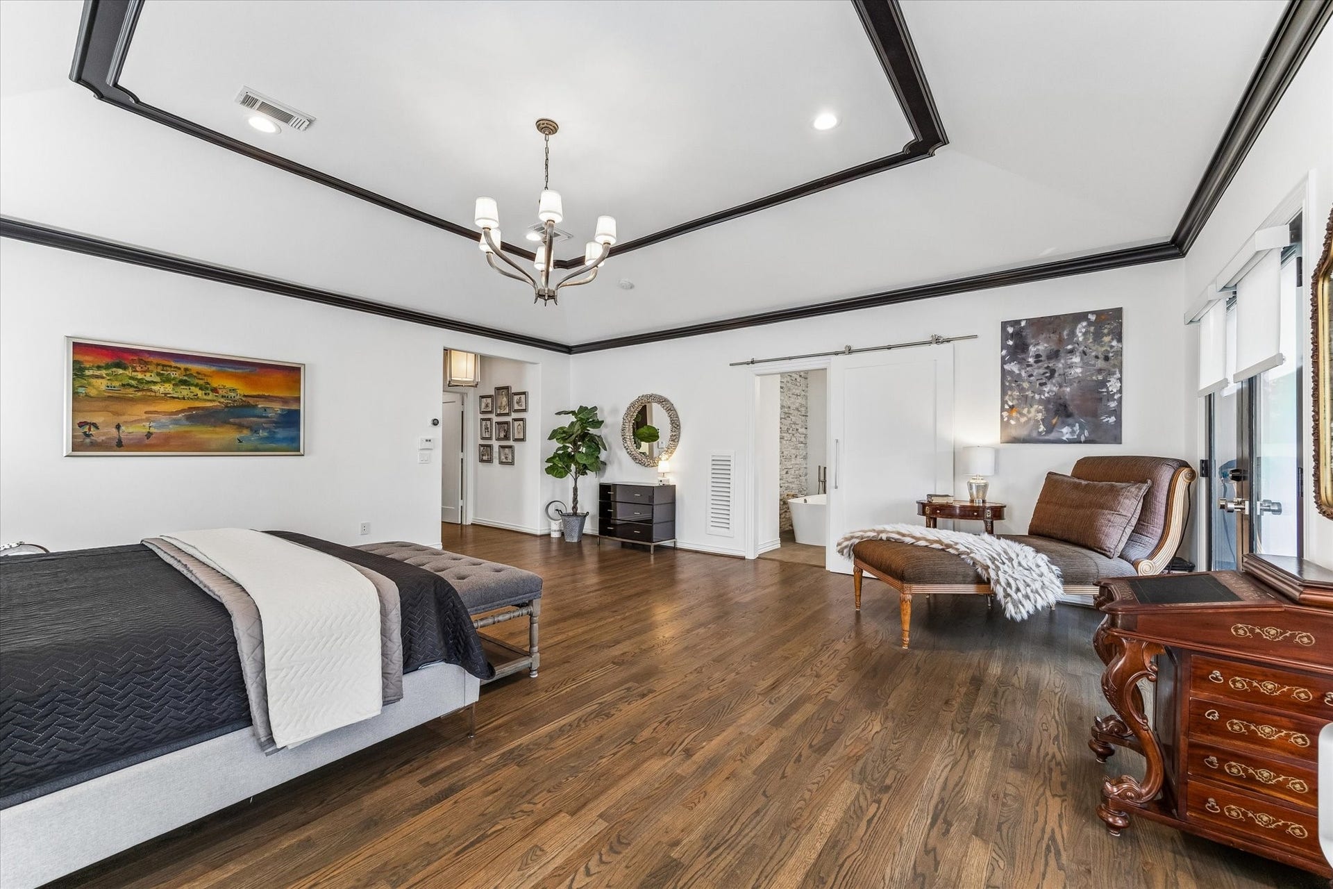 Another view of the primary showcasing the accented ceiling and barn door leading to the bathroom.