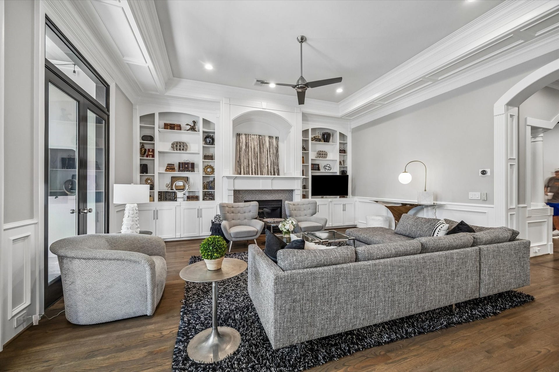 Light-filled family room with gas fireplace, built-in shelving, and tray ceiling