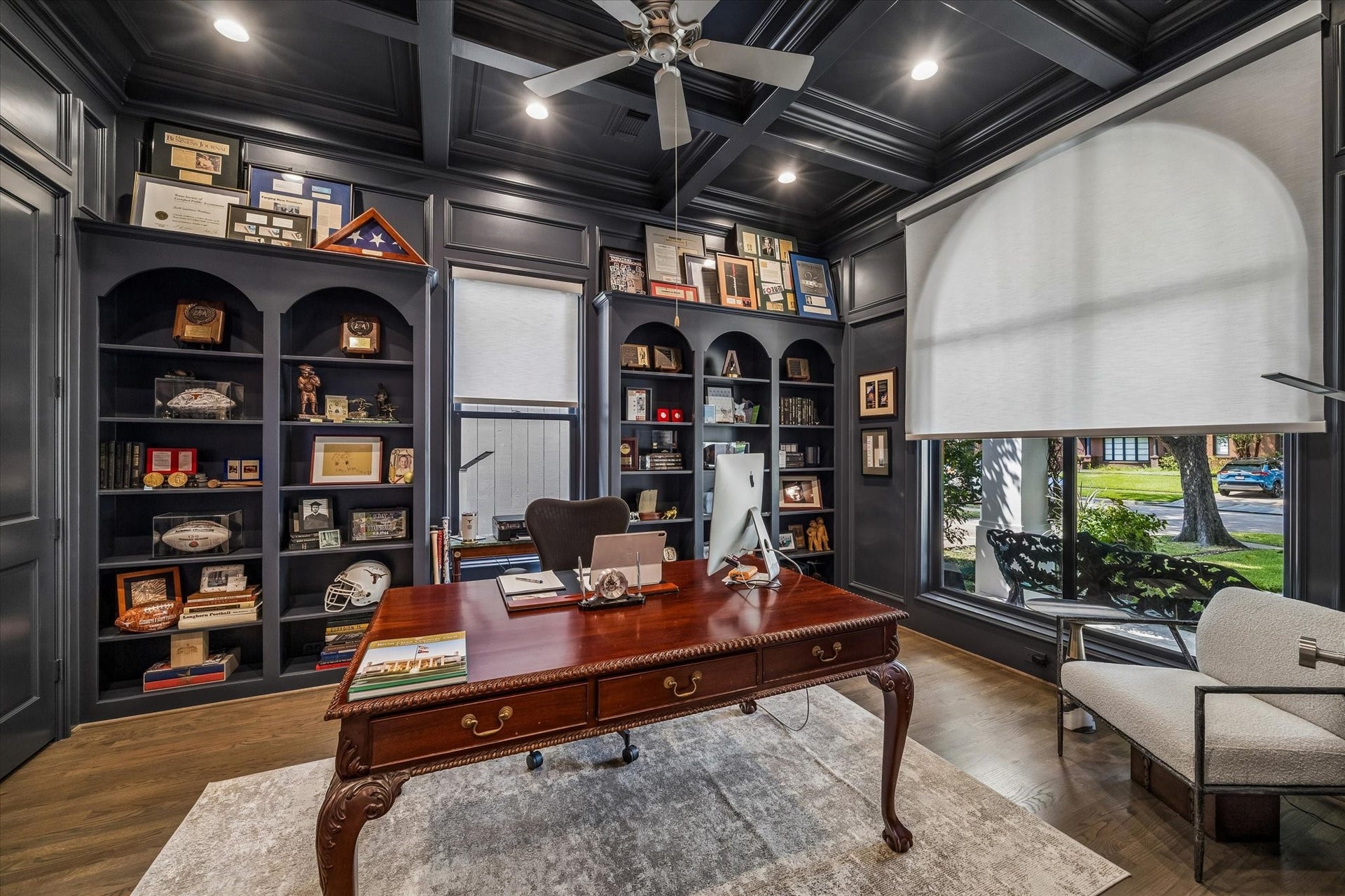 This sophisticated study features built-in bookshelves, a coffered ceiling, and custom electronic retractable roller shades.