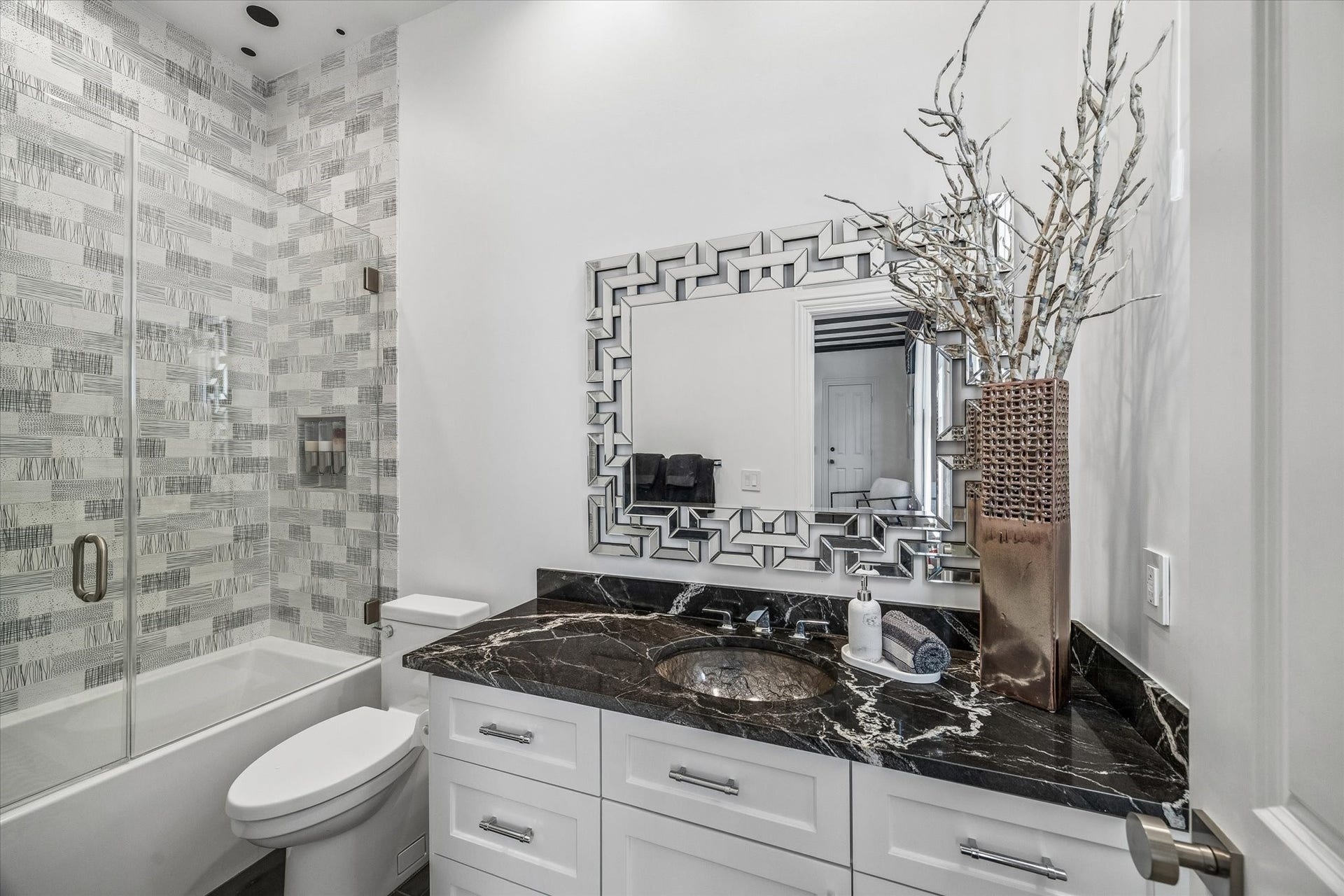 Ensuite secondary bathroom with Marfil River quartz countertop, Italian tile flooring, custom cabinetry, and a soaker tub/shower with retractable glass shower door.