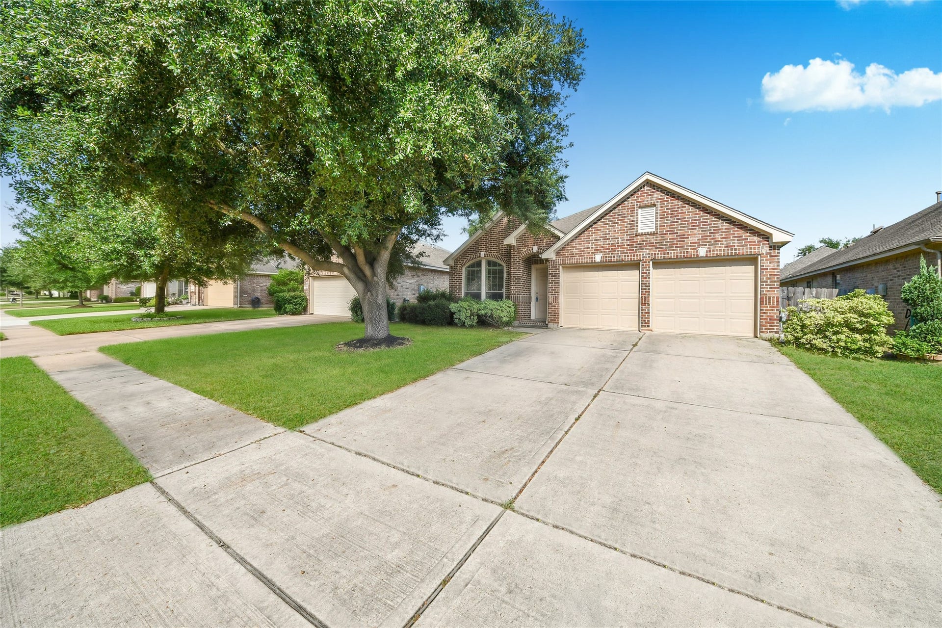 Charming brick home with a spacious two-car garage, set amidst a beautifully manicured lawn and mature trees, offering a welcoming curb appeal.