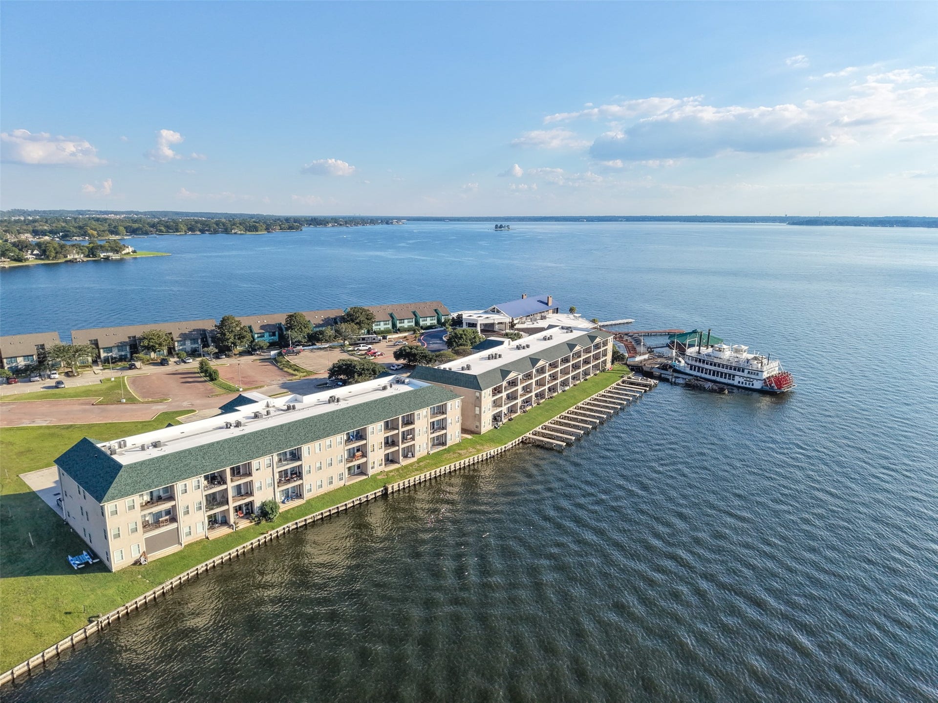 7037 Kingston Cove, #114, Willis, TX 77318 Aerial view of the condominium building showcases its waterfront setting, covered patios and balconies, and grassy shoreline