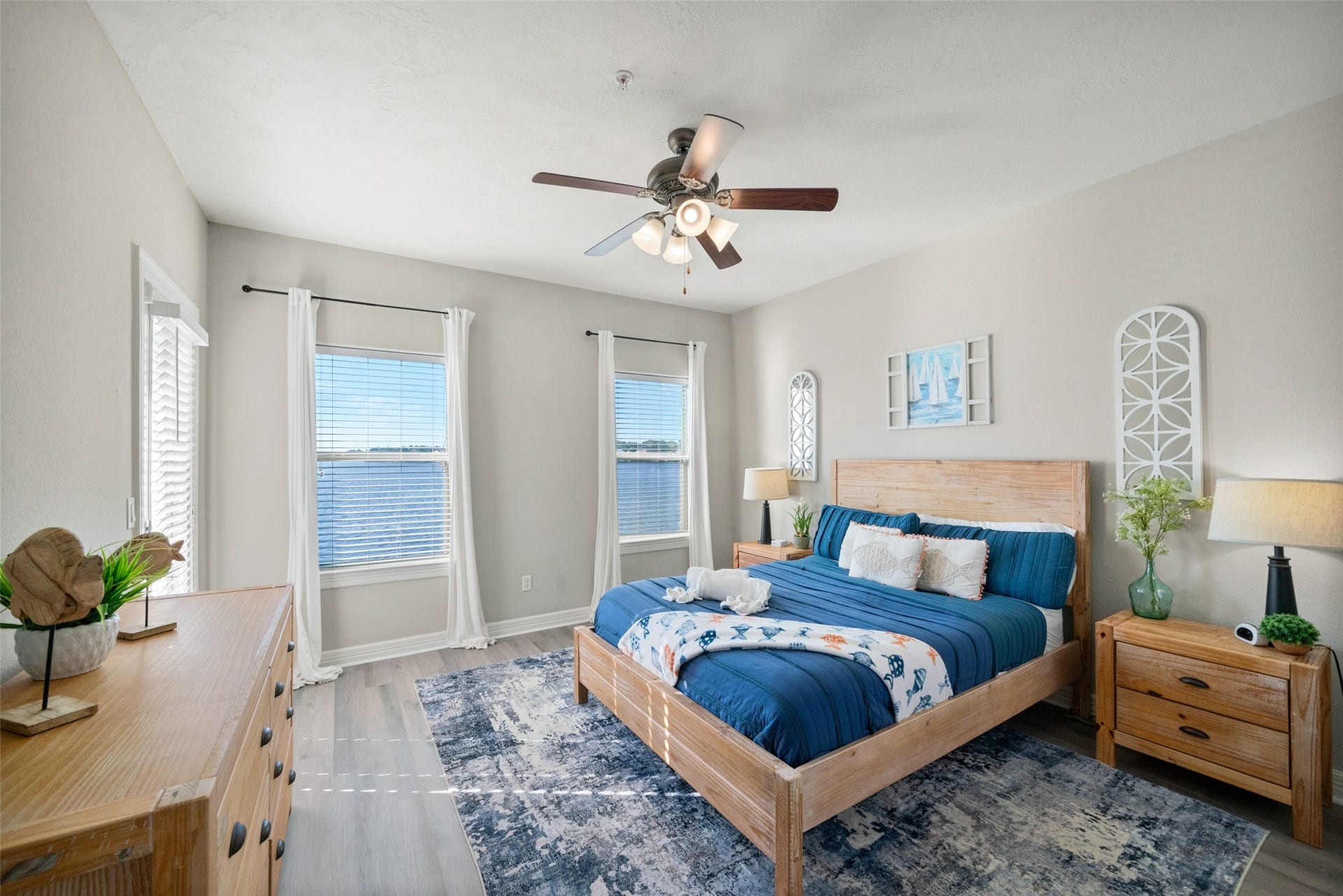 7037 Kingston Cove, #114, Willis, TX 77318 Bedroom features a ceiling fan, wood-look flooring, and large windows framing views of the lake.