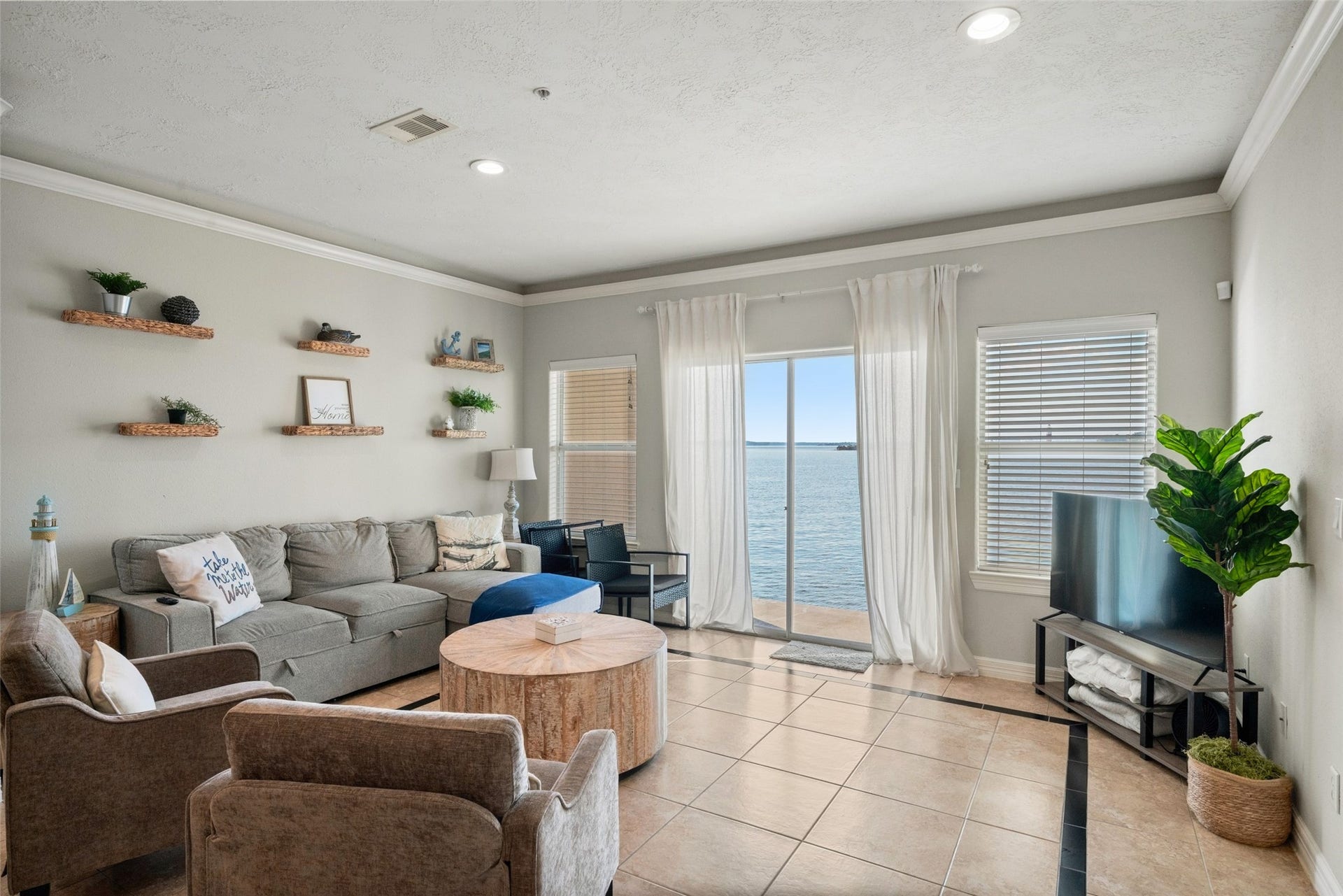 7037 Kingston Cove, #114, Willis, TX 77318 Inviting living area with recessed lighting, wood-look flooring, and large windows showcasing lake views beside the patio door.