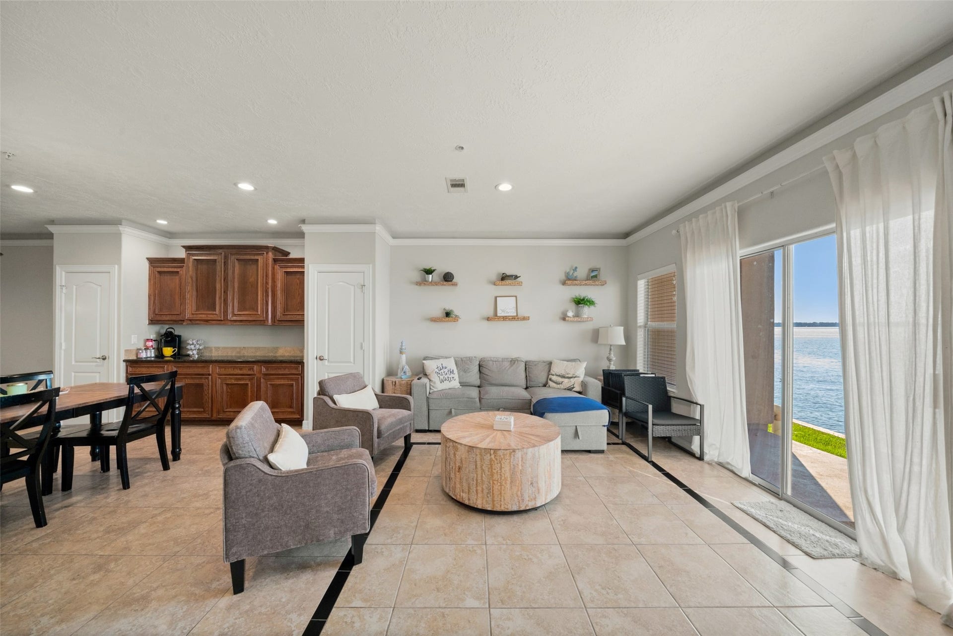 7037 Kingston Cove, #114, Willis, TX 77318 Living and dining areas flow together, with large windows and a glass patio door bringing in natural light and lake views.