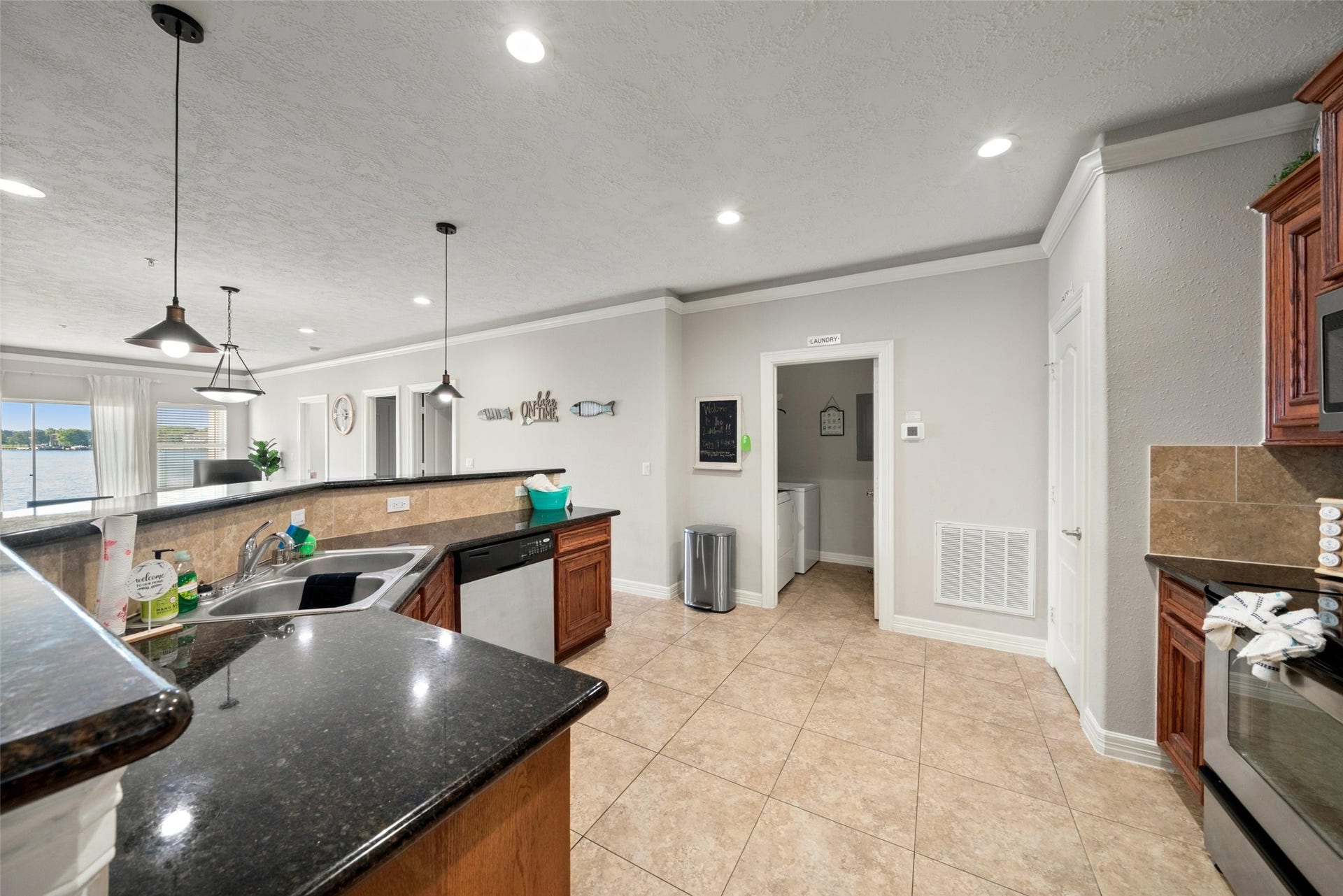 7037 Kingston Cove, #114, Willis, TX 77318 Kitchen features warm wood cabinetry, dark countertops, a tile backsplash, and a breakfast bar overlooking the dining and living areas.