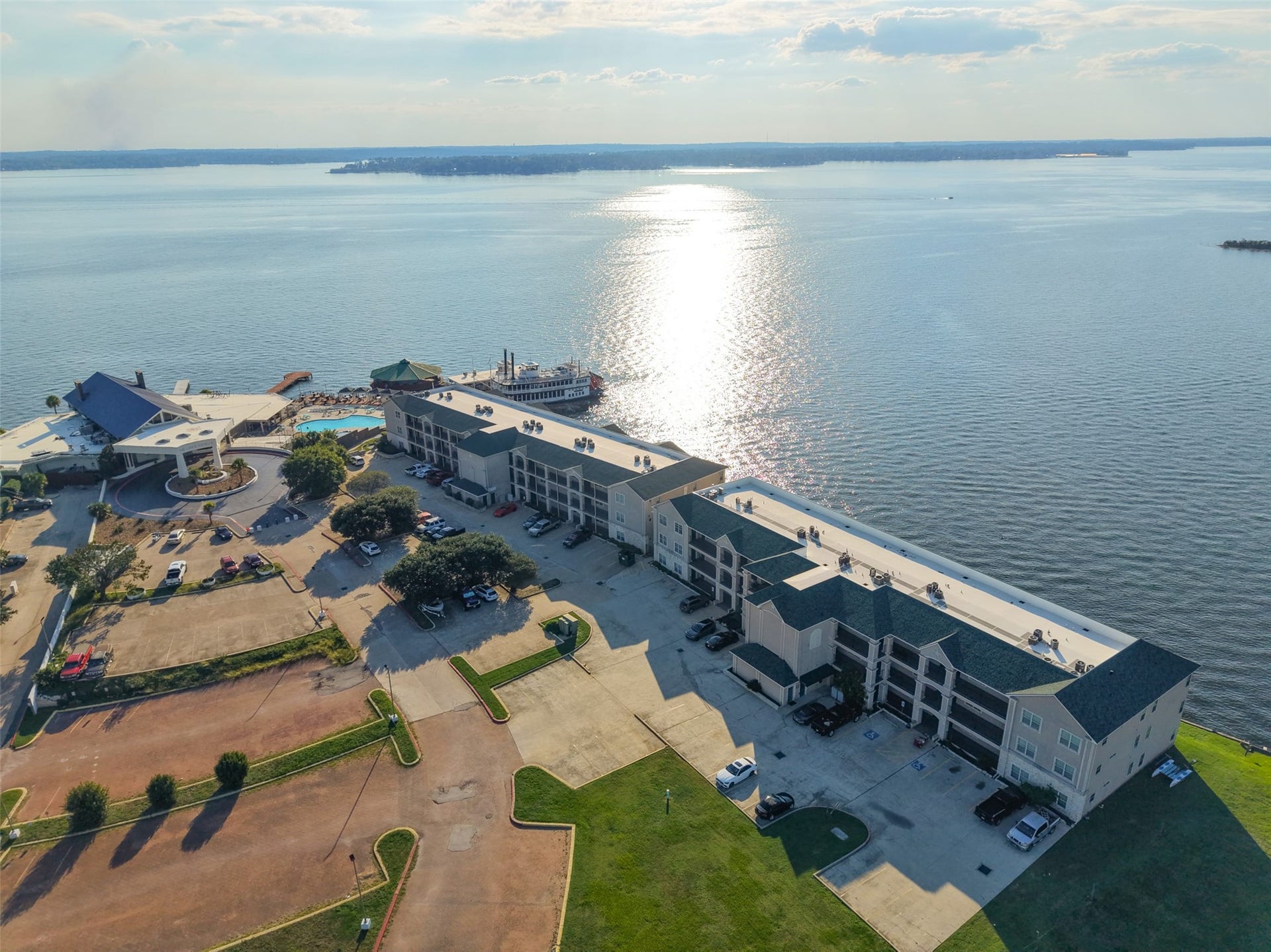 7037 Kingston Cove, #114, Willis, TX 77318 Elevated view captures the condominium buildings beside the lake, with sunlight reflecting across the open water.