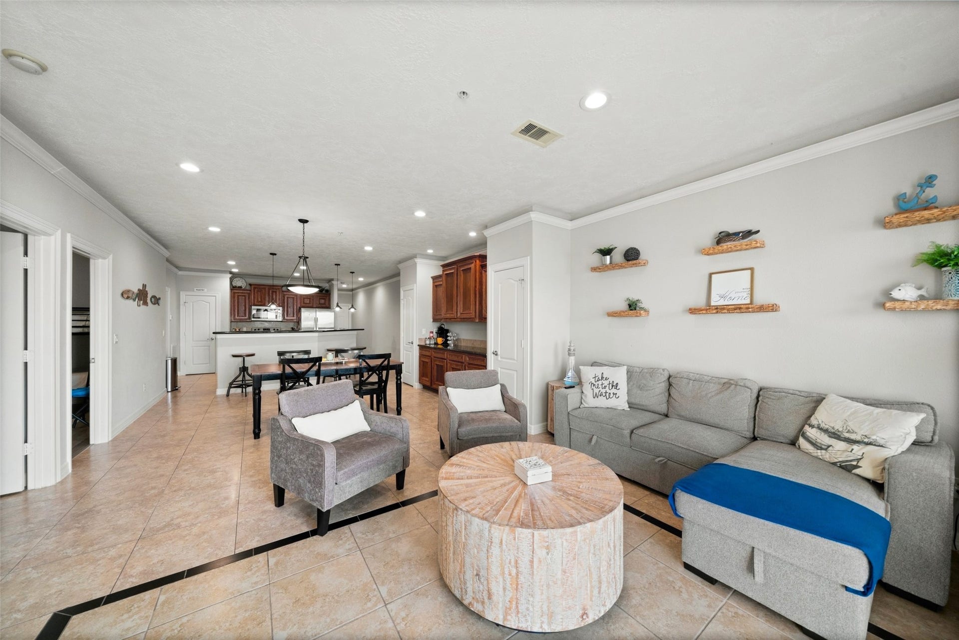 7037 Kingston Cove, #114, Willis, TX 77318 Open living space features recessed lighting, wood-look flooring, decorative wall shelving, and a breakfast bar connecting to the kitchen.