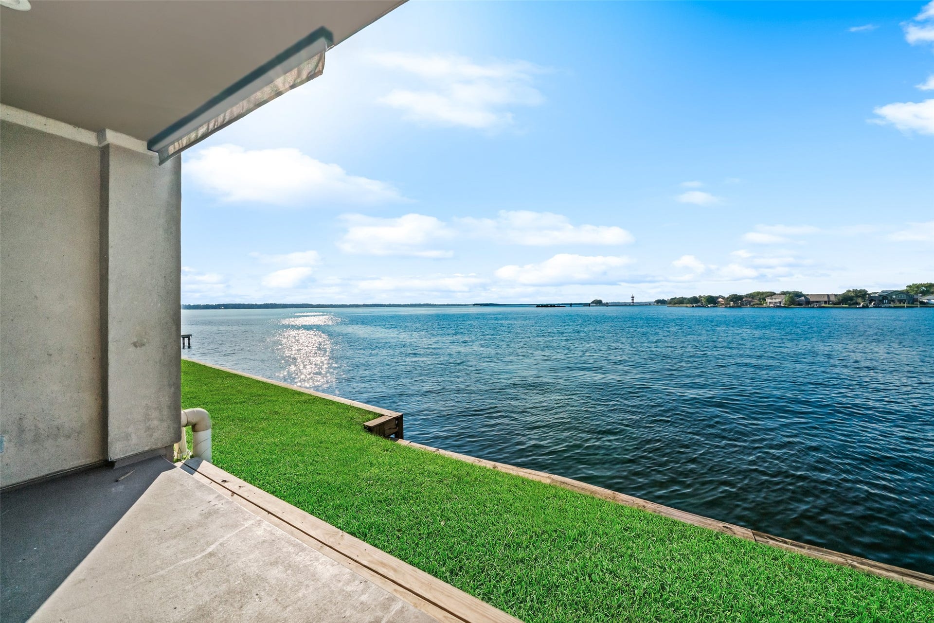 7037 Kingston Cove, #114, Willis, TX 77318 Additional view from the covered patio showcasing the lake and grassy shoreline just beyond.
