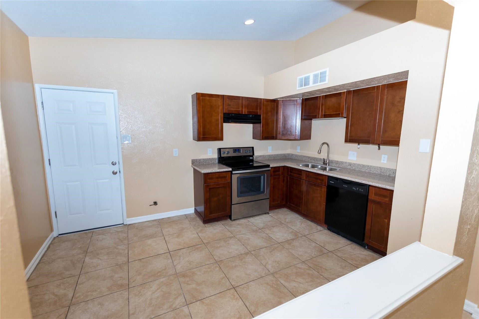 5610 Wallis Trail Court, Houston, TX 77049 Modern kitchen with stainless steel appliances, rich wood cabinetry, and tile flooring, offering a spacious and functional layout.