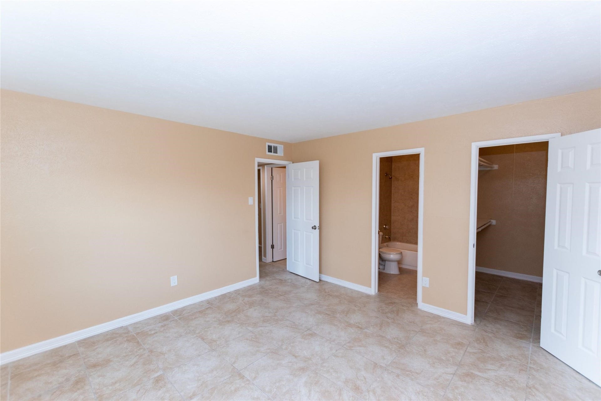 5610 Wallis Trail Court, Houston, TX 77049 Spacious bedroom with neutral tones, featuring tiled flooring, an en-suite bathroom, and a walk-in closet.