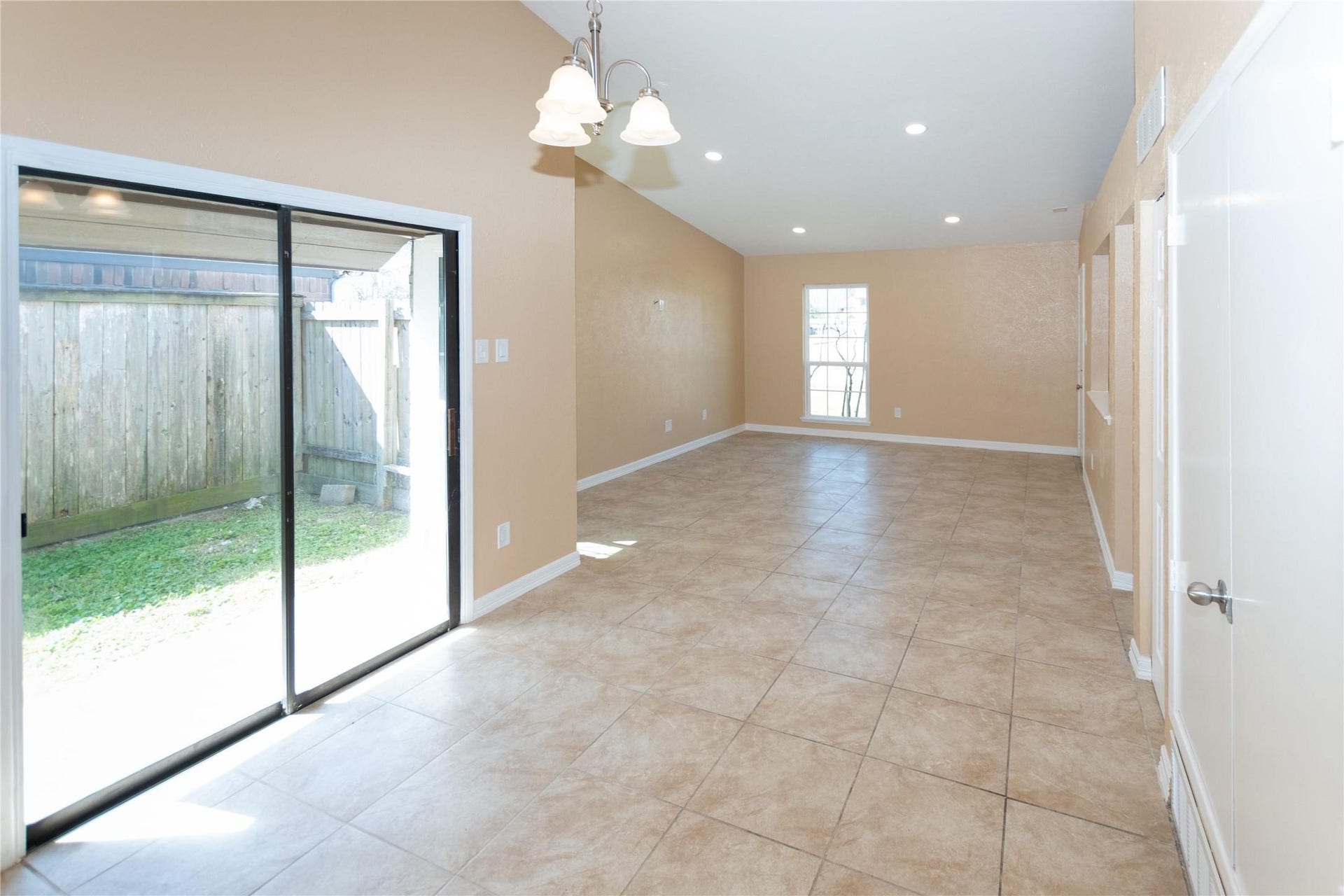 5610 Wallis Trail Court, Houston, TX 77049 Bright and spacious open-plan living area featuring large tile flooring, recessed lighting, and abundant natural light from sliding glass doors leading to the backyard.