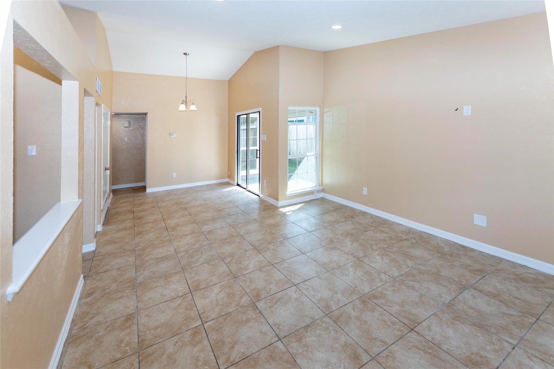 5610 Wallis Trail Court, Houston, TX 77049 Spacious living area with high ceilings, tile flooring, and abundant natural light from large windows and a glass door leading to the backyard.