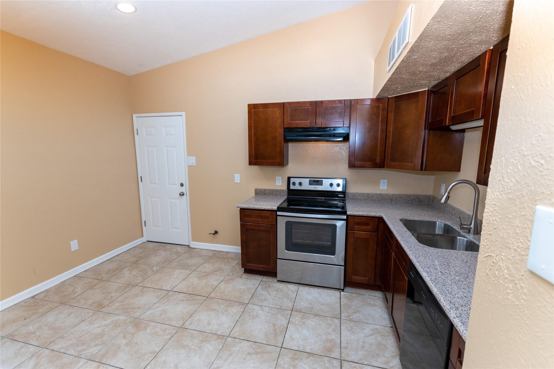 5610 Wallis Trail Court, Houston, TX 77049 Modern kitchen with rich wood cabinetry, stainless steel appliances, and a sleek countertop, complemented by tiled flooring and warm wall tones.