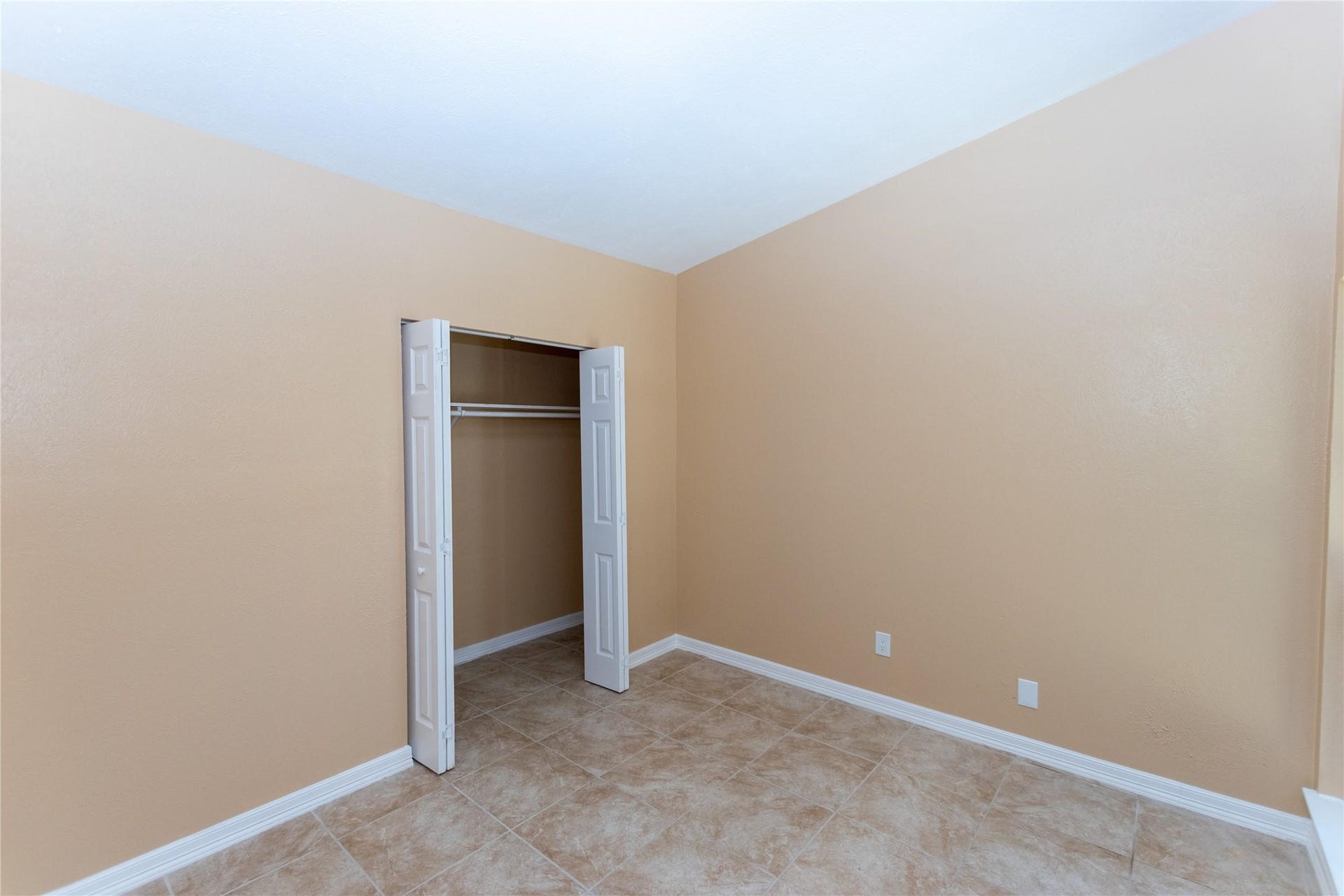 5610 Wallis Trail Court, Houston, TX 77049 Cozy room with soft beige walls, tiled flooring, and a convenient closet with white folding doors.