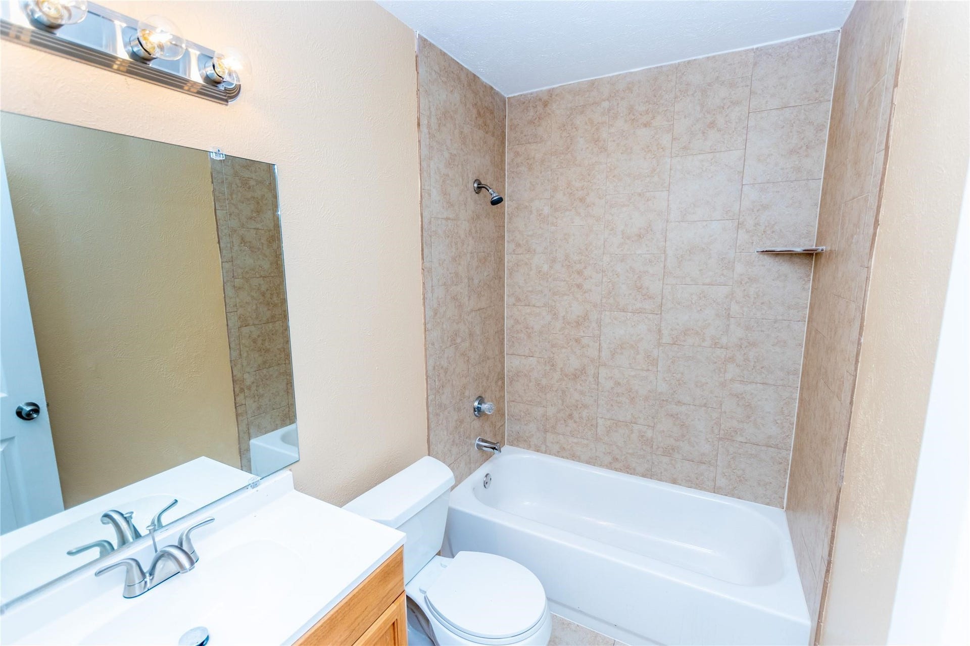 5610 Wallis Trail Court, Houston, TX 77049 Bright bathroom with a tiled shower-tub combo, sleek vanity, and modern lighting.