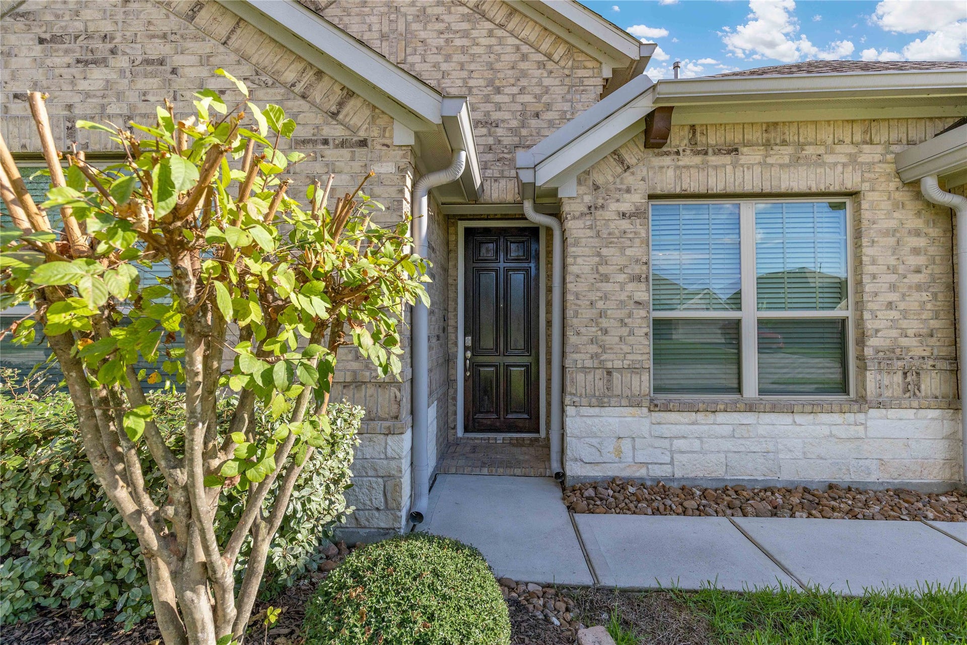 Charming brick exterior with a welcoming front entrance, accented by well-maintained landscaping and large windows for natural light.