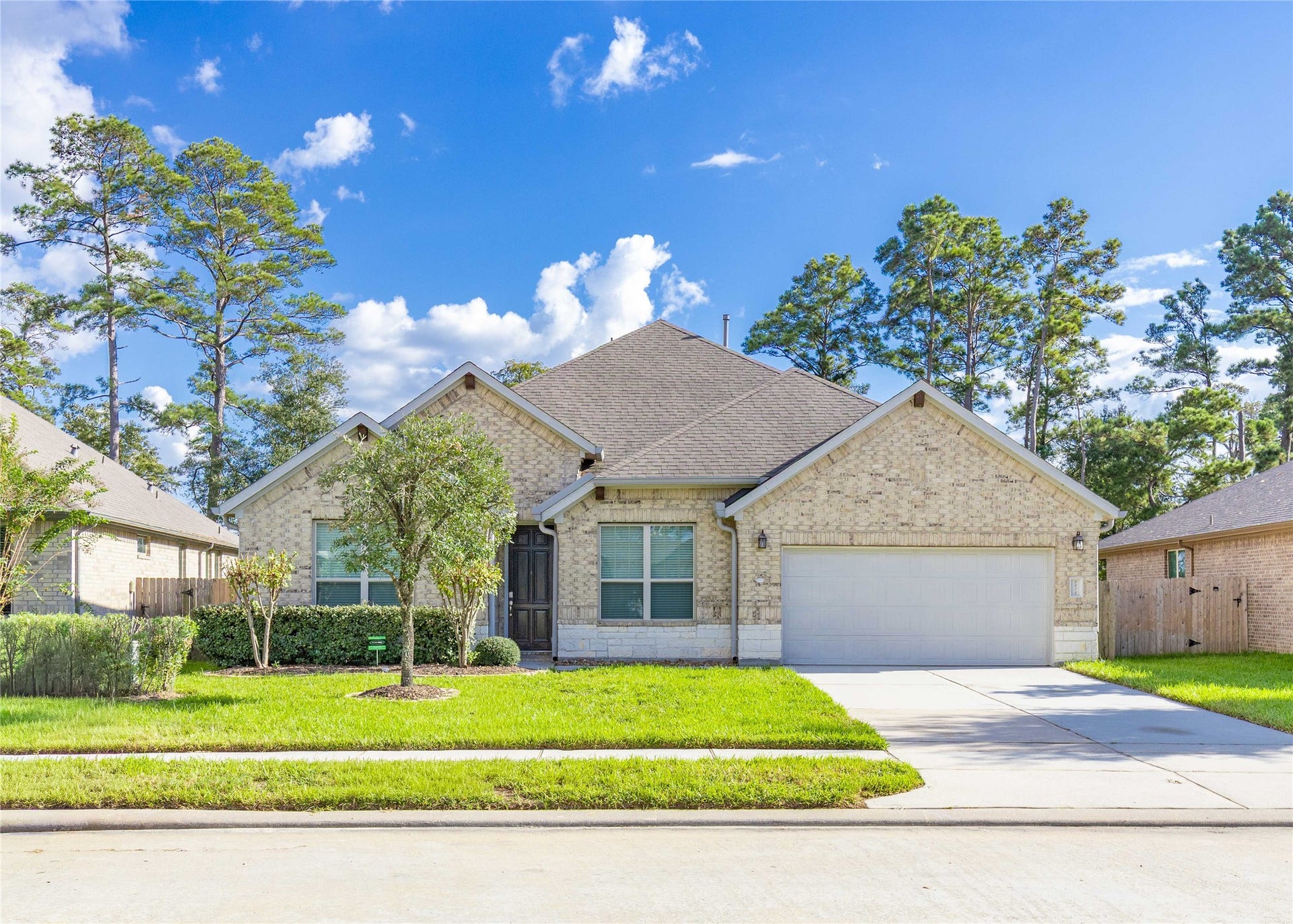 Charming brick home with a well-maintained front yard, featuring a spacious driveway leading to a two-car garage.