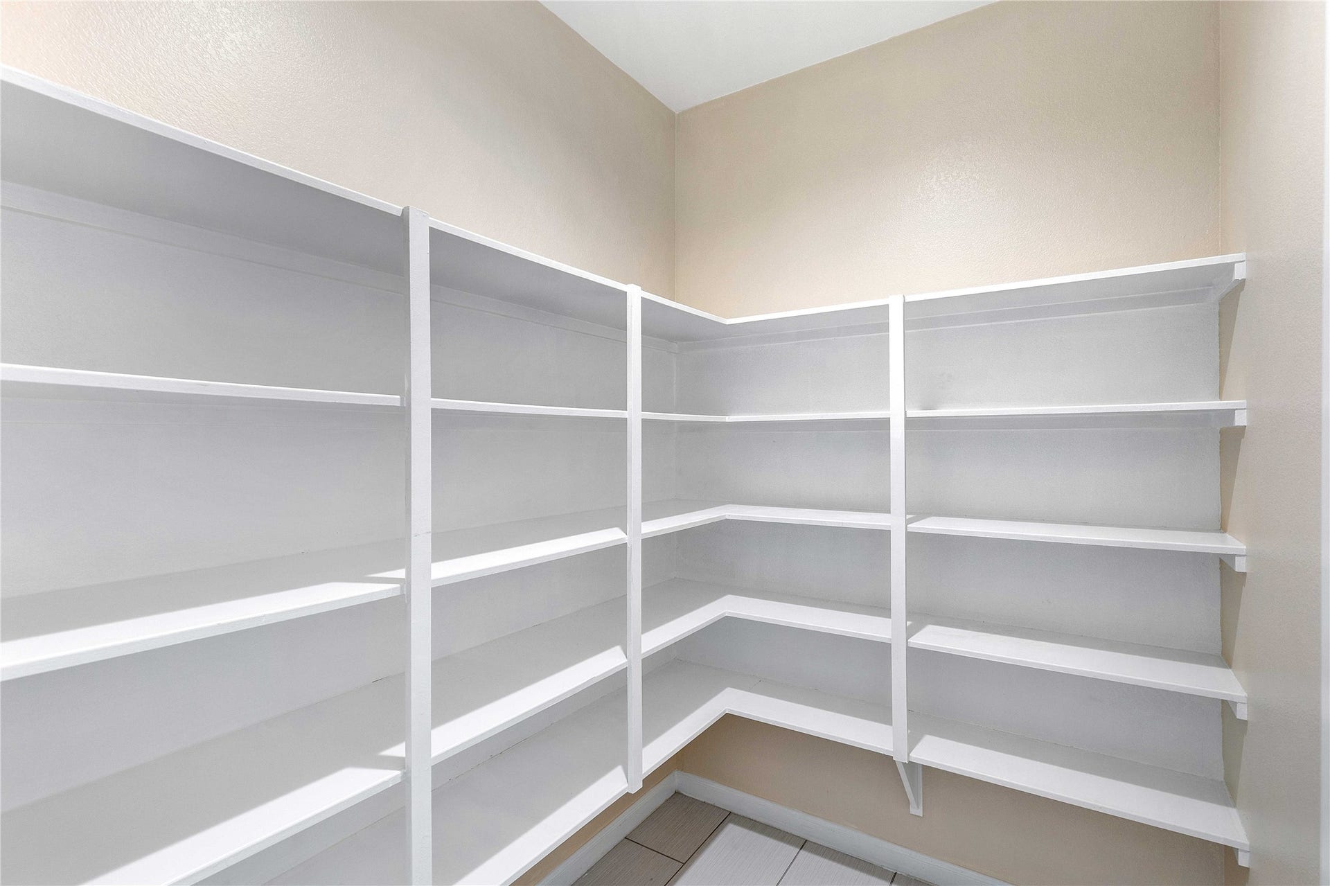 Spacious walk-in pantry with ample shelving for organized storage.