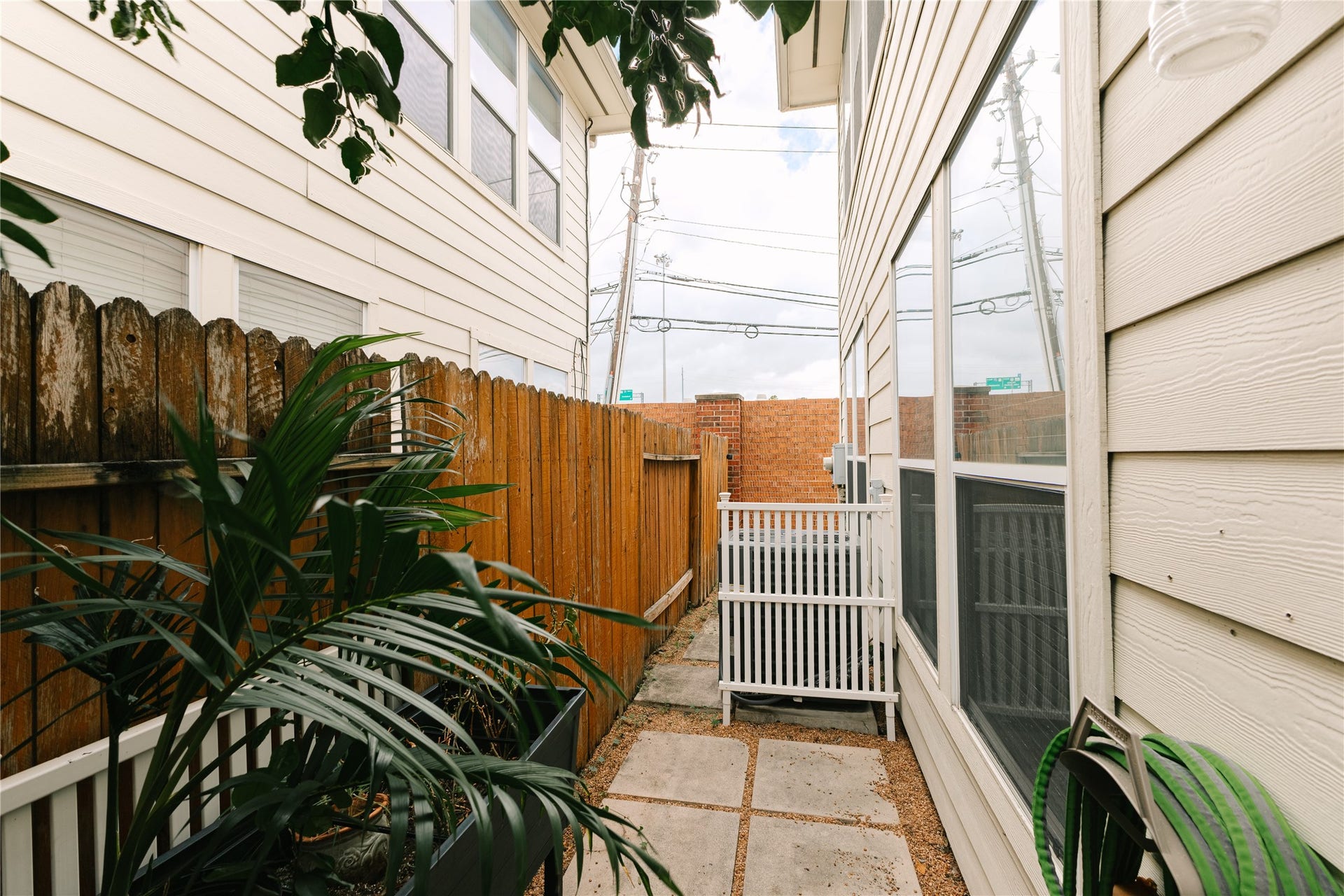 1710 Aden Mist Drive, Houston, TX 77003 Charming side yard with privacy fencing, lush greenery, and stone path, perfect for a serene outdoor retreat.