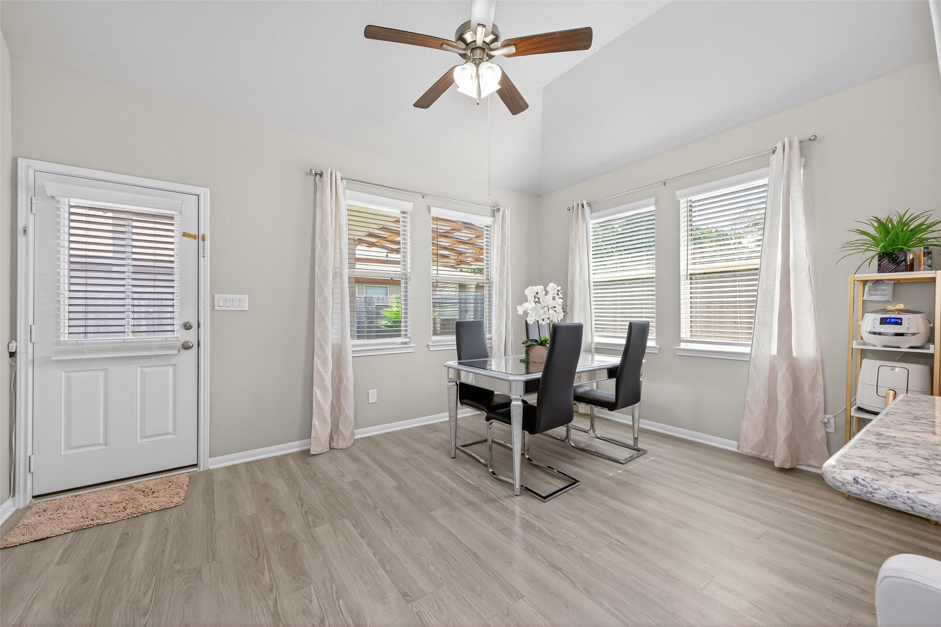 22409 Kinley Street, New Caney, TX 77357 This bright dining area features large windows, modern flooring, a ceiling fan, and a stylish dining set, creating an inviting space for meals and gatherings.