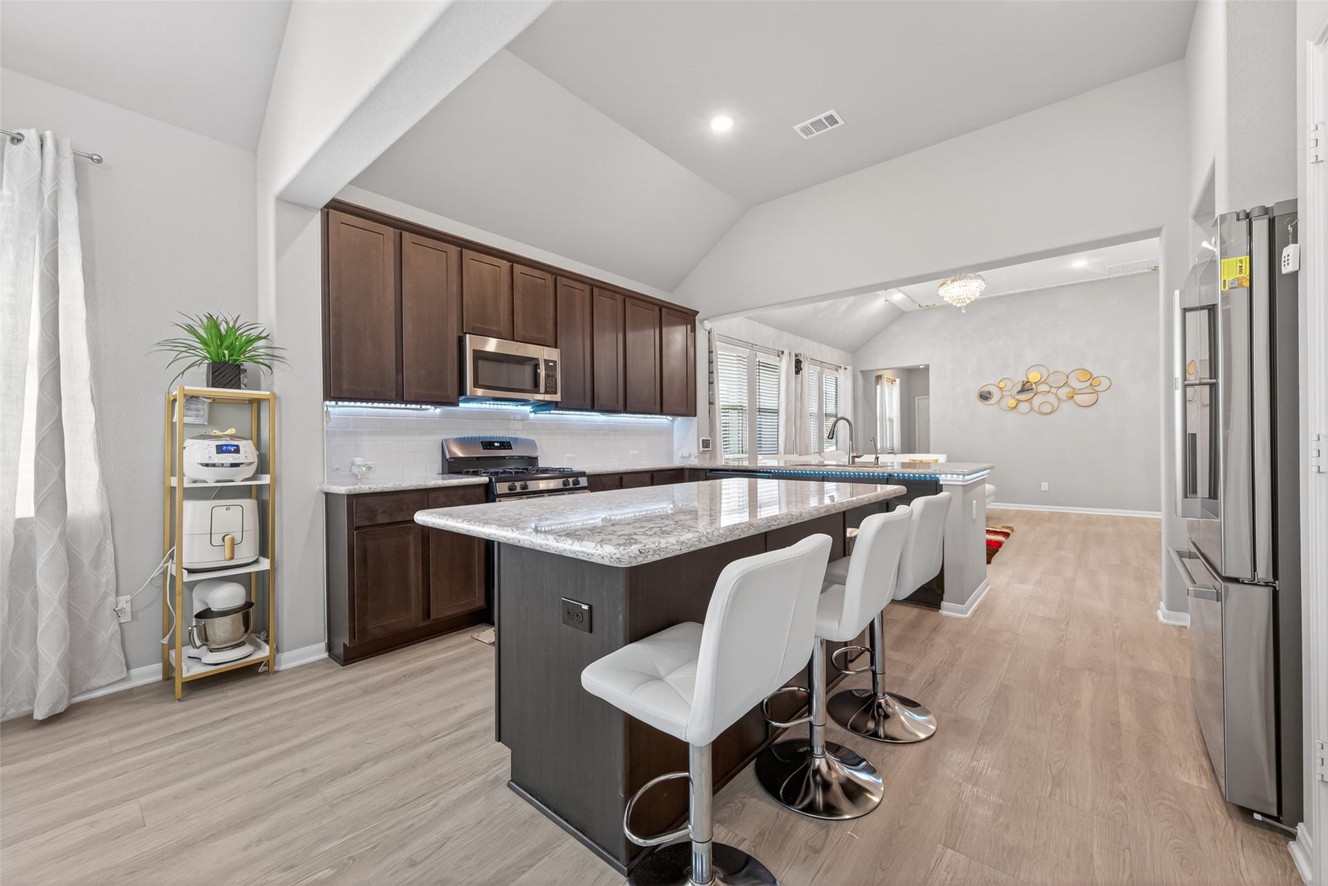 22409 Kinley Street, New Caney, TX 77357 Kitchen with an open layout, featuring a central island with granite countertops and seating for four. The space is bright with ample natural light from large windows.