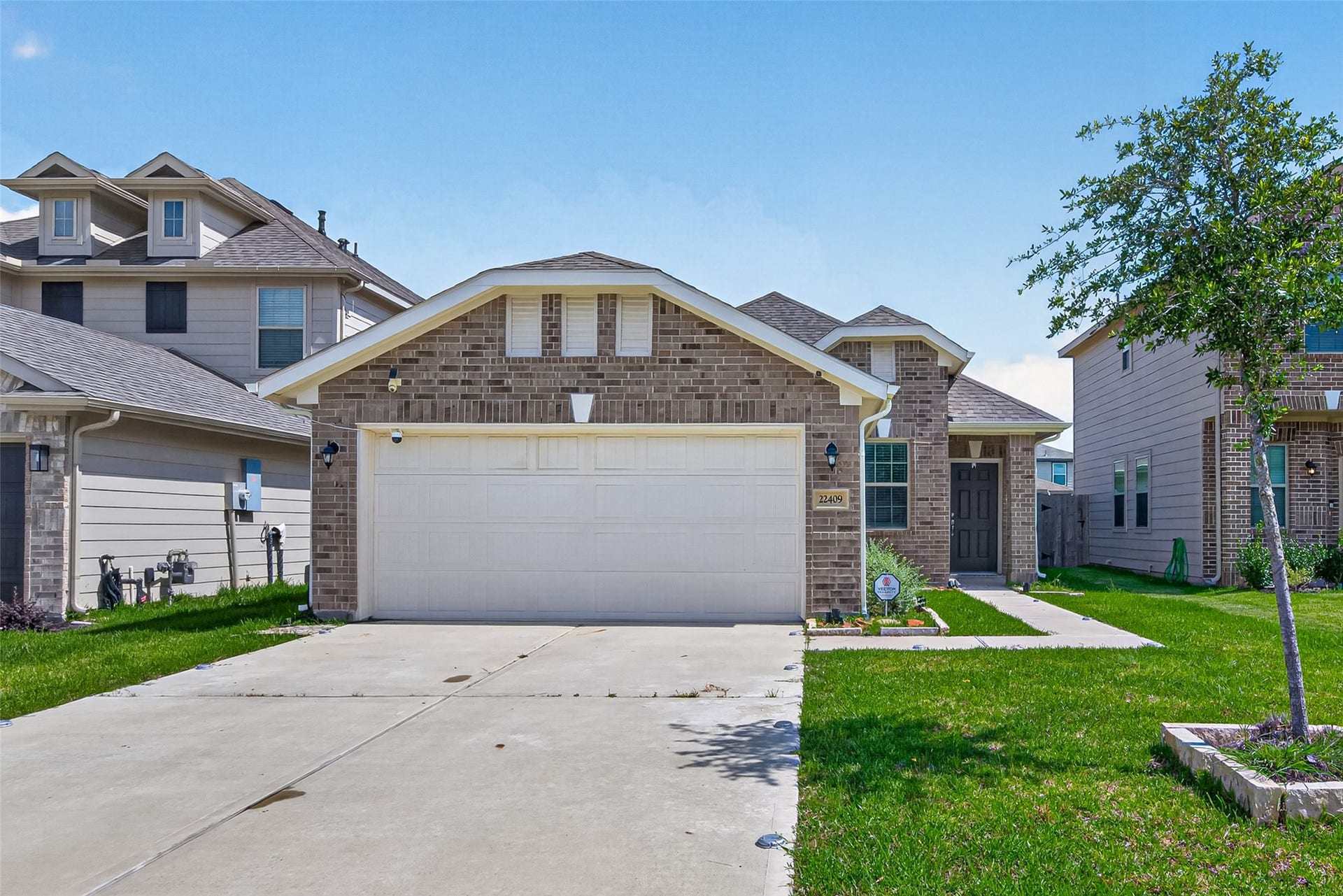 22409 Kinley Street, New Caney, TX 77357 A charming single-story brick house with a two-car garage. It is situated in a suburban neighborhood with neighboring houses visible.