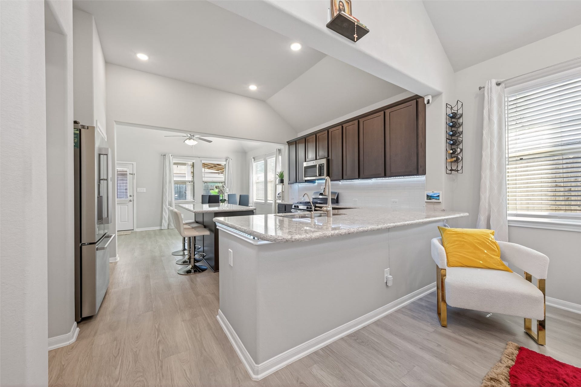 22409 Kinley Street, New Caney, TX 77357 Bright and open kitchen with high ceilings, modern appliances, and a spacious island. Features dark cabinetry, light countertops, and a cozy adjacent seating area. Natural light flows through large windows, enhancing the airy feel.