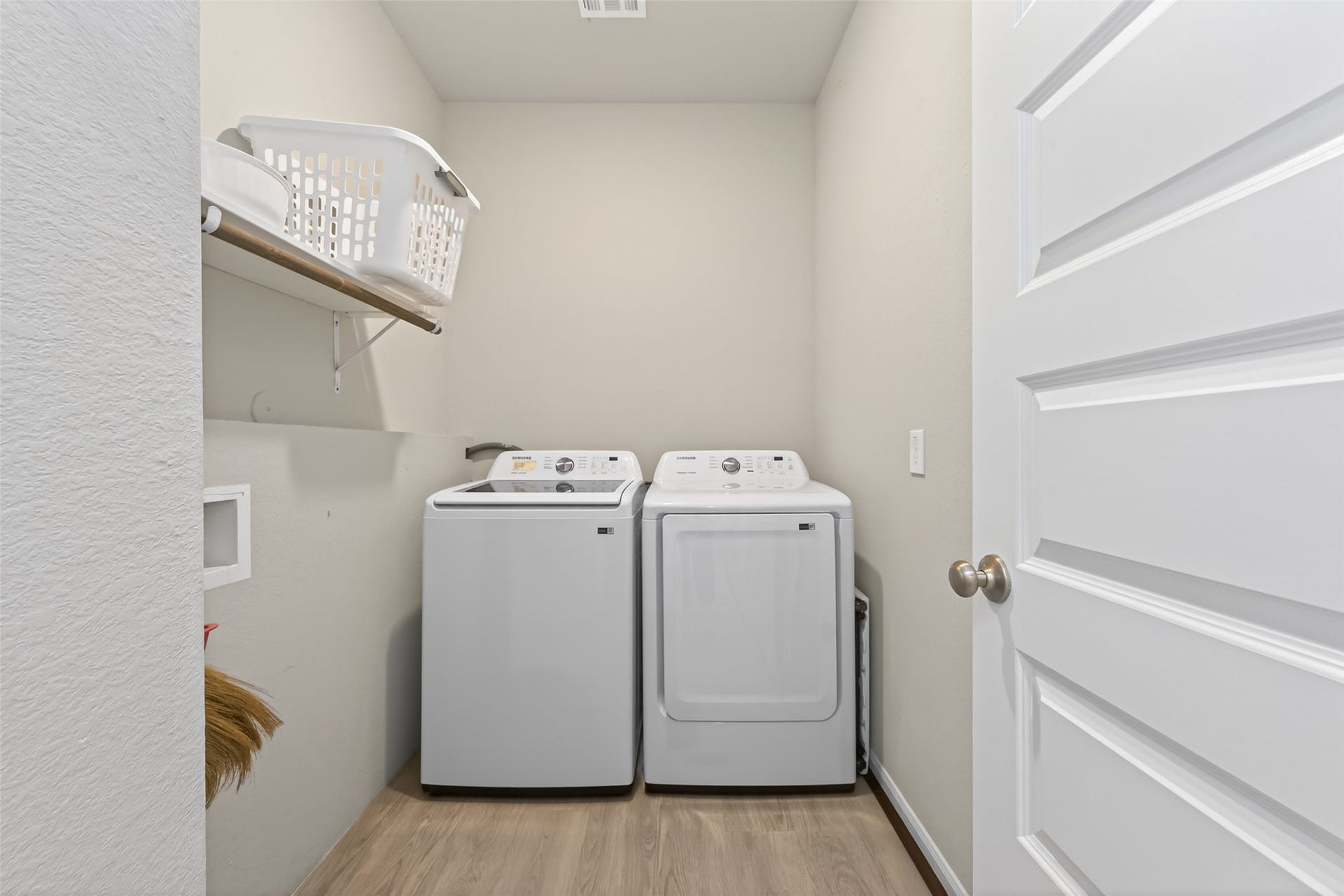 22409 Kinley Street, New Caney, TX 77357 This is a compact laundry room featuring a washer and dryer side by side, with a shelf above for storage.