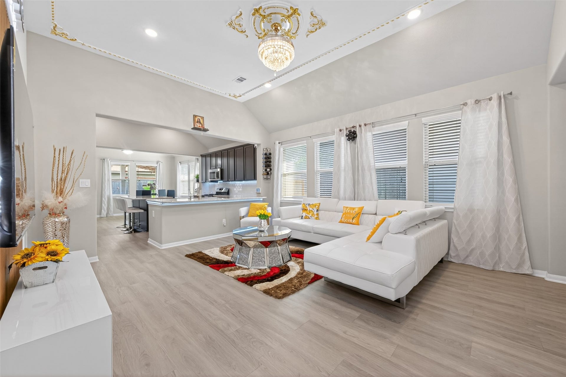 22409 Kinley Street, New Caney, TX 77357 Bright and spacious open-concept living room, featuring a vaulted ceiling, modern lighting, and a large sectional sofa. The room flows seamlessly into a contemporary kitchen with a breakfast bar, perfect for entertaining.