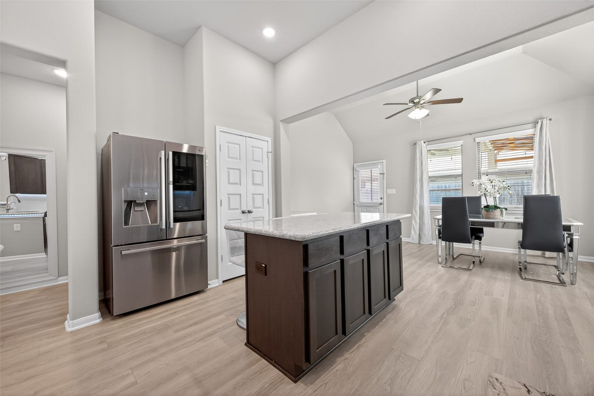 22409 Kinley Street, New Caney, TX 77357 A modern kitchen and dining area with sleek stainless steel appliances, an island with a granite countertop, and light wood flooring.