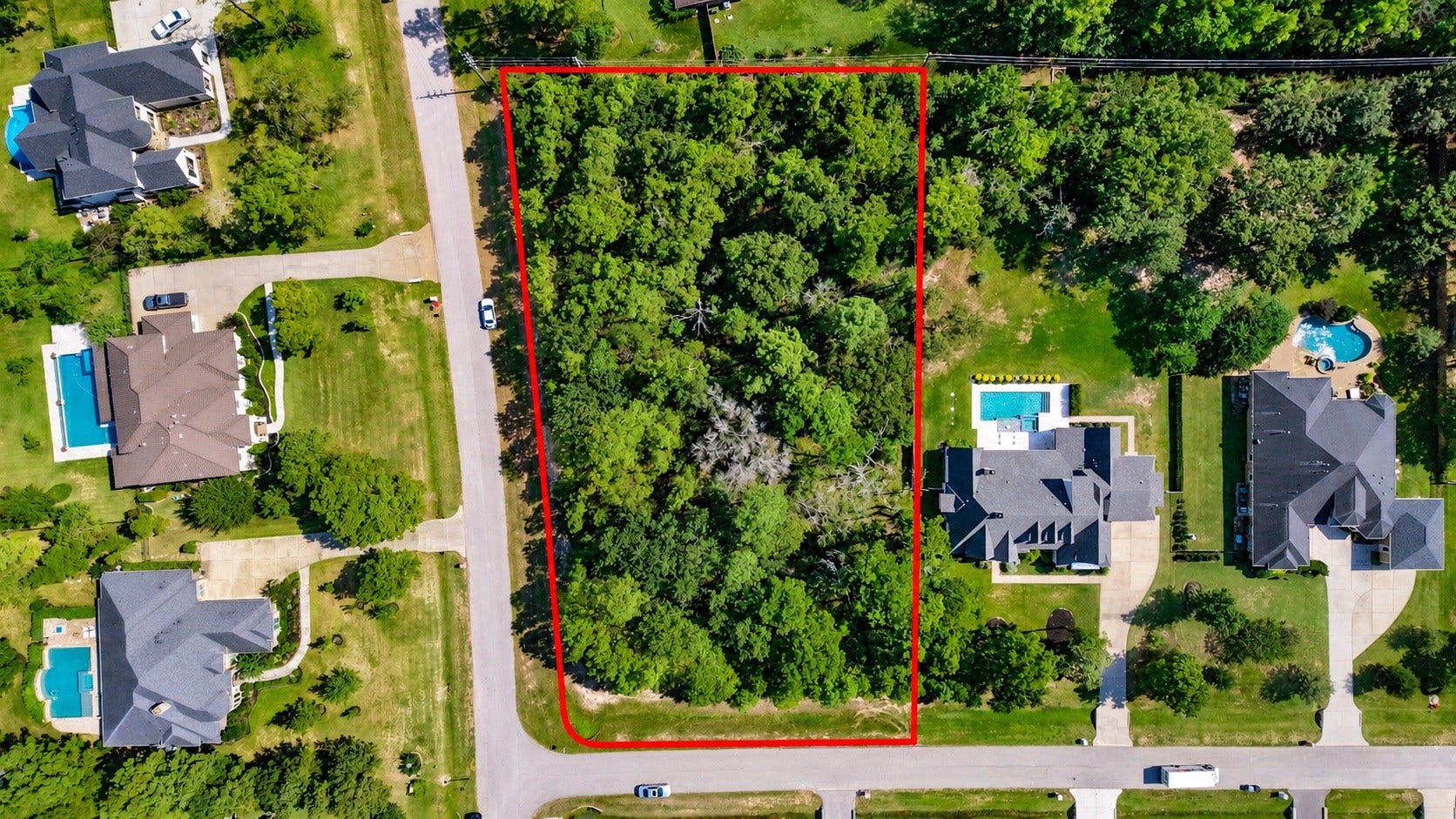 Overhead view showcasing the property's wooded landscape and road frontage.