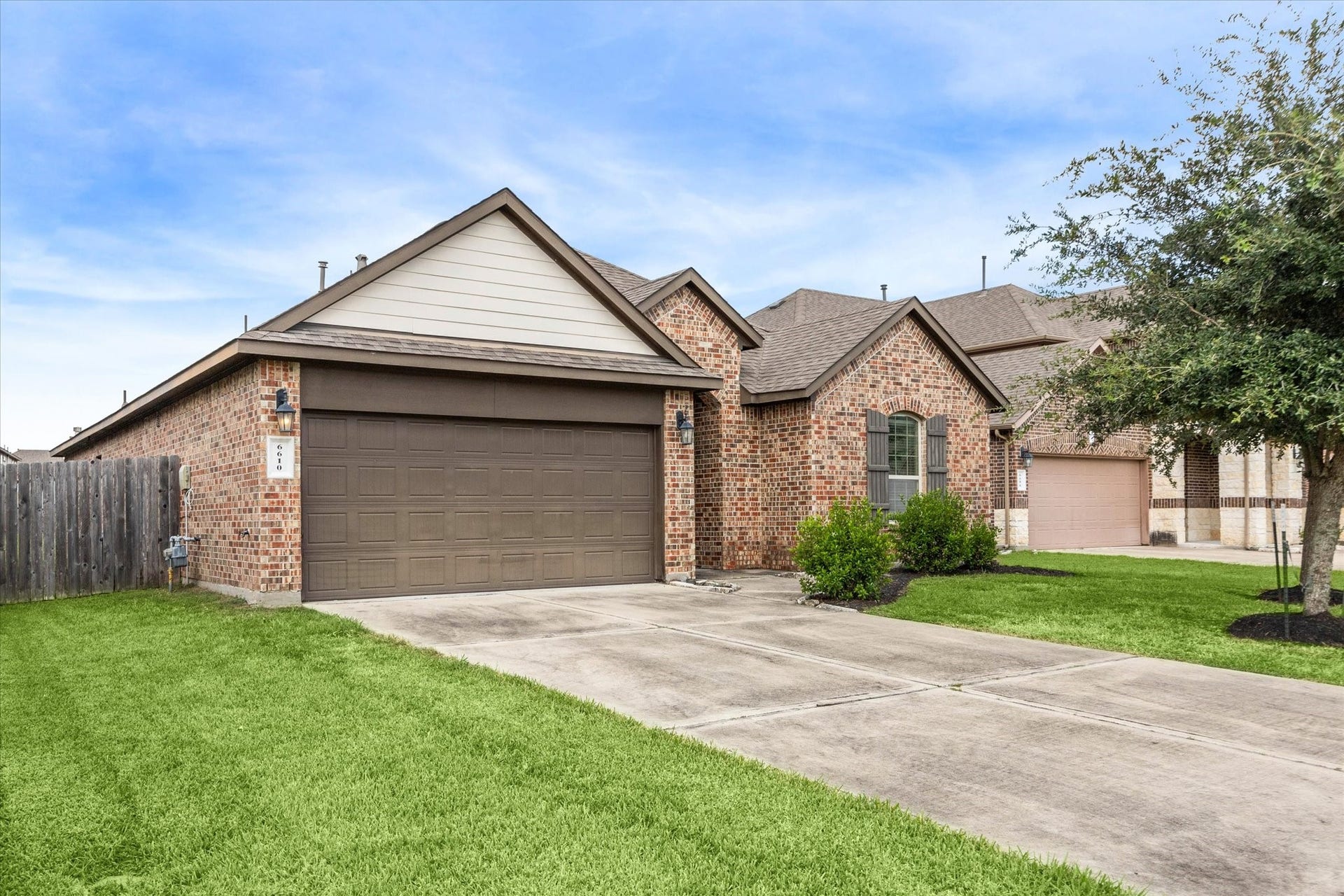 6610 Auburn Terrace Lane, Rosenberg, TX 77471 This is a well-maintained single-story brick home featuring a two-car garage, a tidy front lawn, and a welcoming exterior with a mature tree and landscaping.