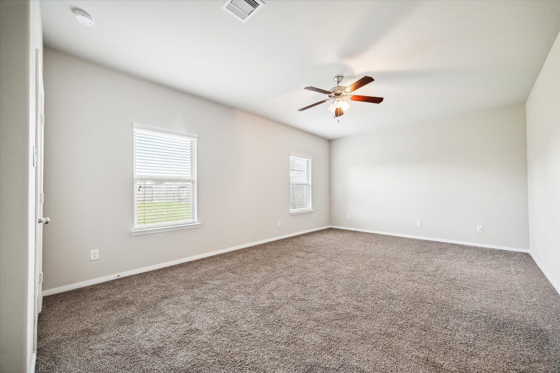 6610 Auburn Terrace Lane, Rosenberg, TX 77471 This is a spacious, well-lit room with neutral walls and carpet flooring, featuring a ceiling fan and multiple windows for natural light.