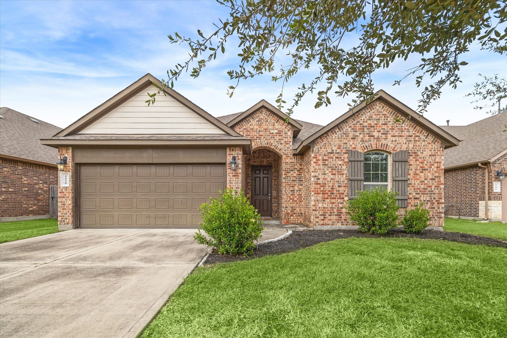 6610 Auburn Terrace Lane, Rosenberg, TX 77471 Charming single-story brick home featuring an attached two-car garage, well-maintained landscaping, and a welcoming entryway.