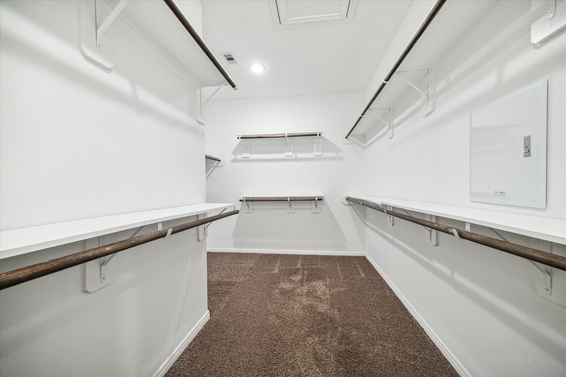 6610 Auburn Terrace Lane, Rosenberg, TX 77471 This is a spacious walk-in closet with ample shelving and hanging rods, featuring a practical layout for organized storage, and it's finished with carpeted flooring.