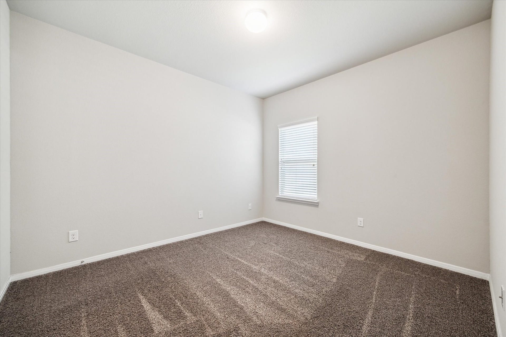 6610 Auburn Terrace Lane, Rosenberg, TX 77471 You're looking at a well-lit, empty room with neutral-colored walls and carpeted flooring, featuring a single window with blinds. It's a blank canvas ready for personalization.