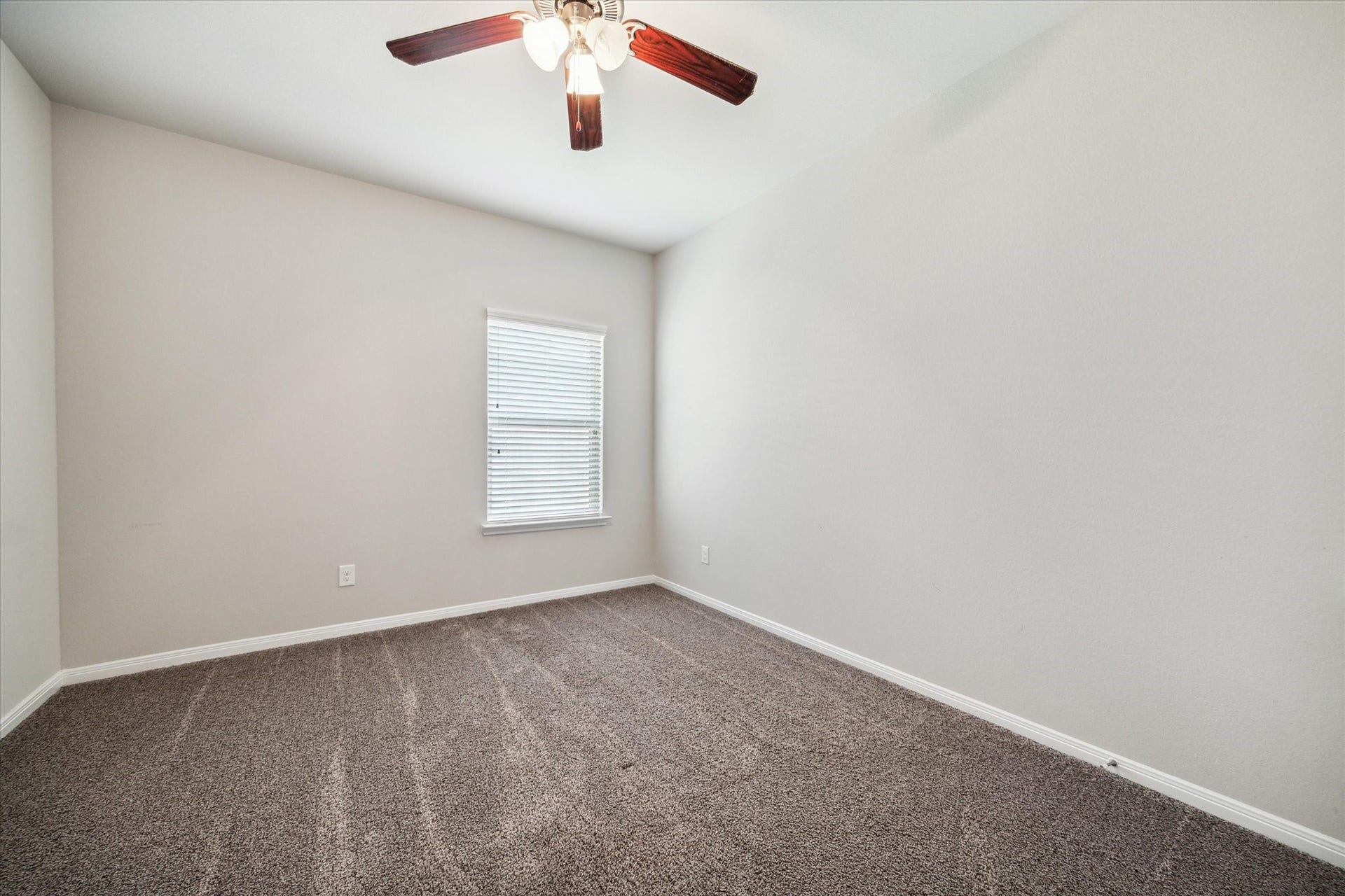 6610 Auburn Terrace Lane, Rosenberg, TX 77471 This is a clean, well-lit, empty room with neutral-colored walls and carpet flooring, featuring a single window and a ceiling fan.