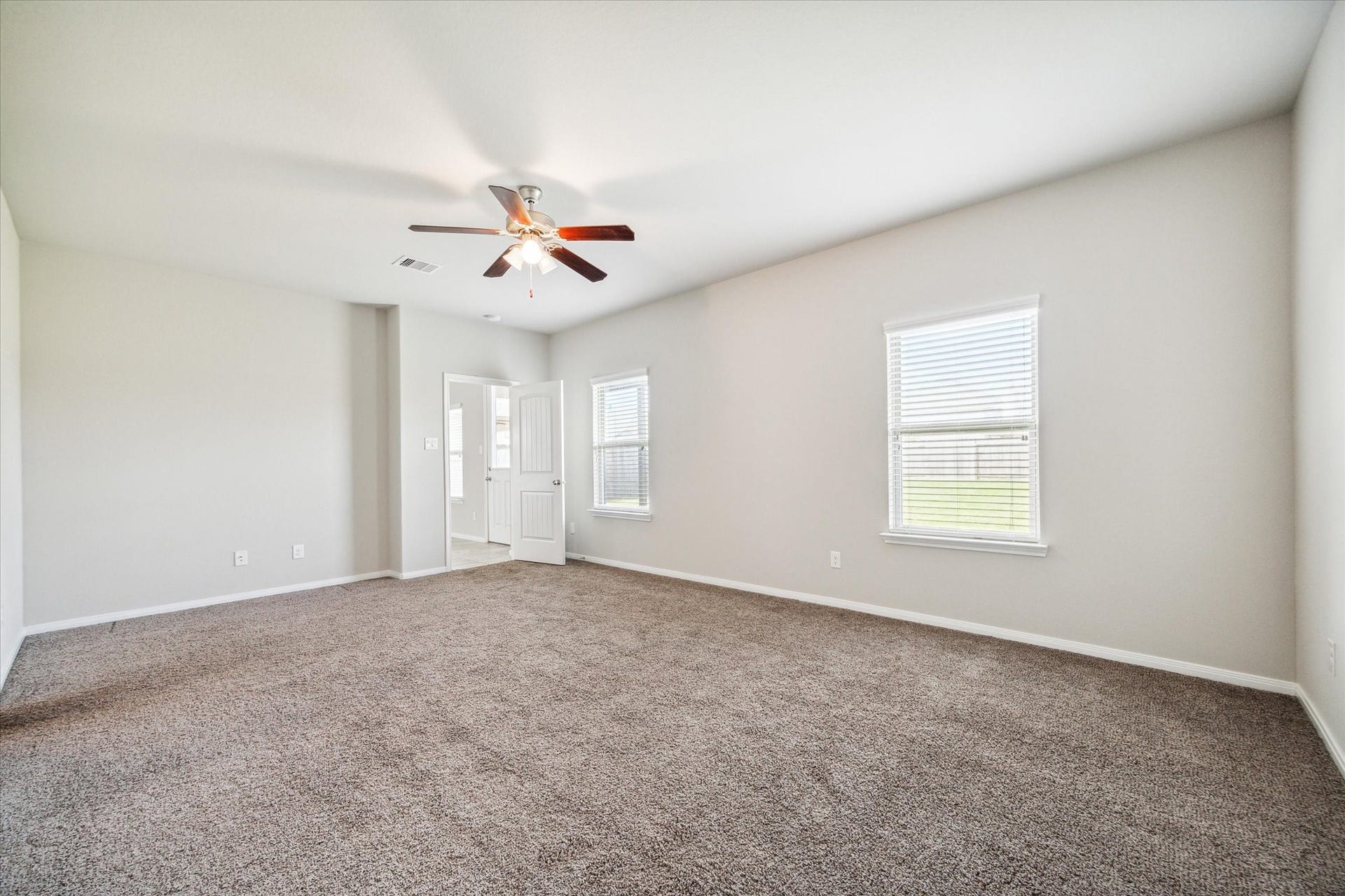 6610 Auburn Terrace Lane, Rosenberg, TX 77471 This is a spacious, well-lit room with neutral walls and carpet flooring, featuring a ceiling fan and two windows providing natural light.