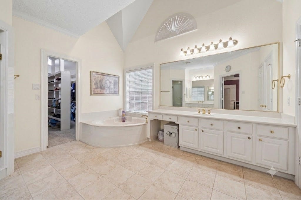 Virtual rendition painted an off white color. Spacious primary bathroom featuring a luxurious corner jetted bathtub, elegant dual vanities with ample storage, and a huge walk-in closet. Natural light pours in through large windows, creating a bright and inviting atmosphere.