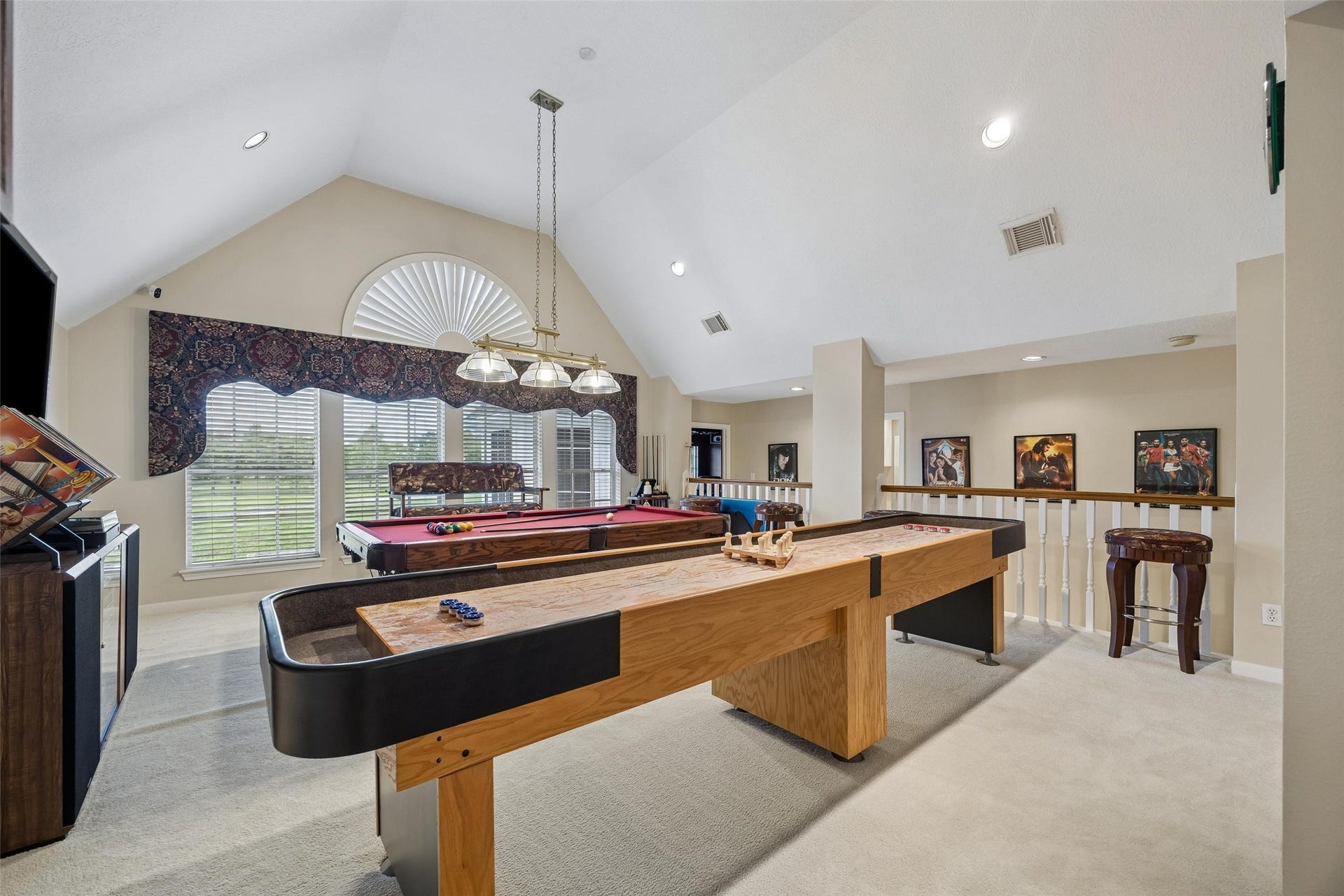 You don't have to leave your home because you have everything right here to have fun. Invite your friends over to enjoy this spacious game room with vaulted ceilings, featuring a pool table, shuffleboard, and ample natural light from large windows. Pool table and shuffleboard are available too.