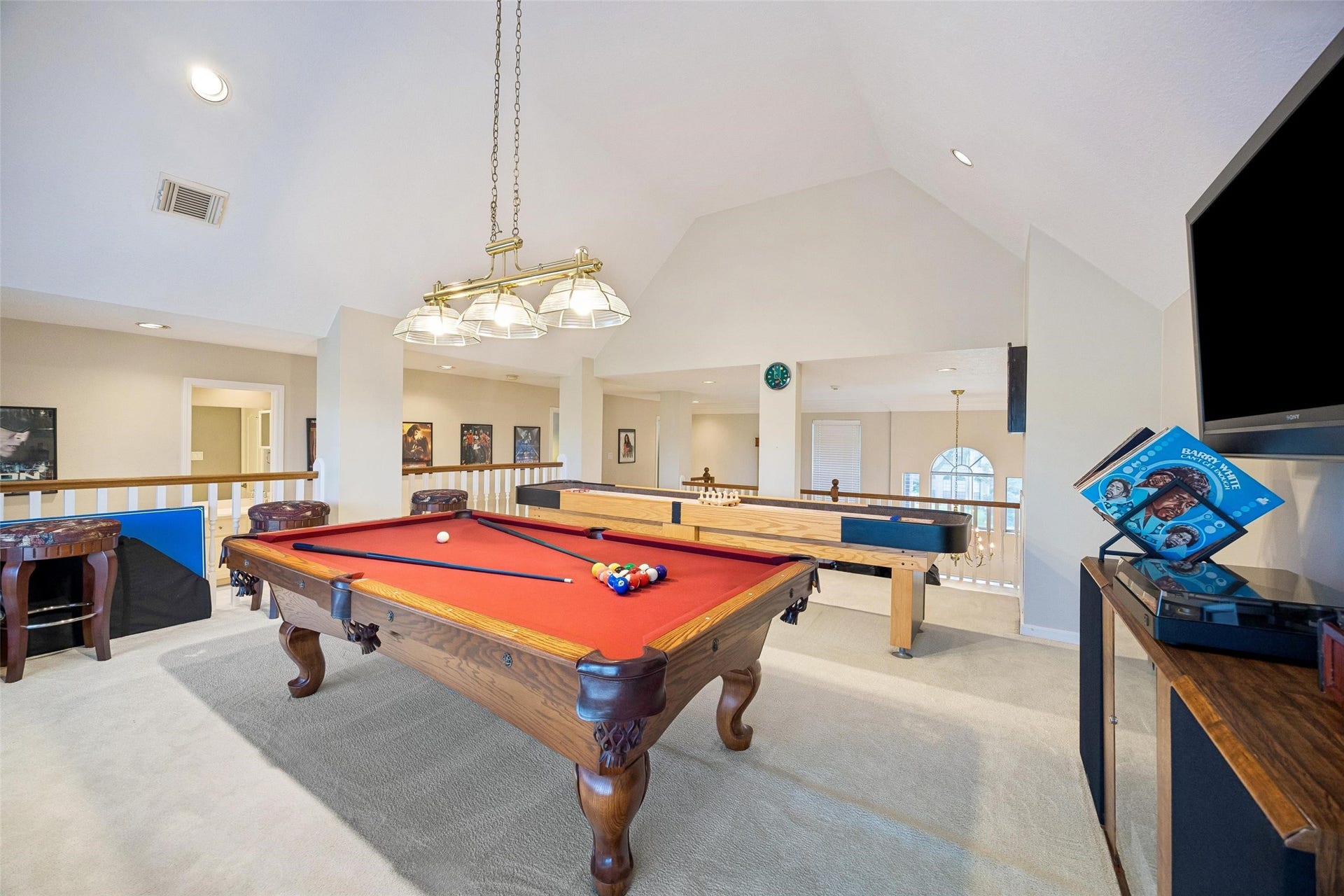 Spacious game room with a classic pool table, shuffleboard, and ample natural light, perfect for entertainment and relaxation. No need to go anywhere with all these toys. The "toys" are available too.