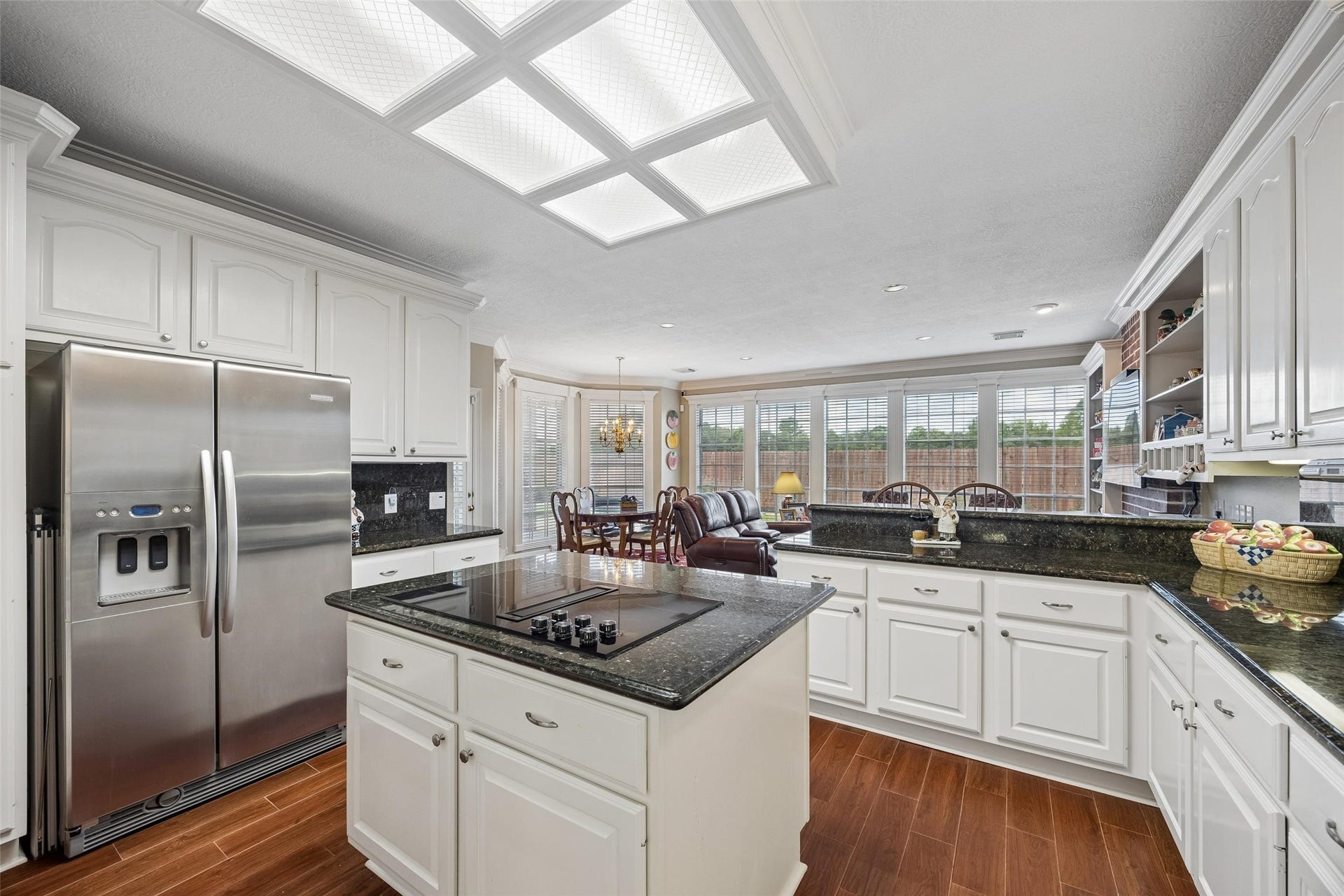 Spacious kitchen with sleek granite countertops, stainless steel appliances, and abundant natural light, seamlessly connecting to a cozy living area with large windows.