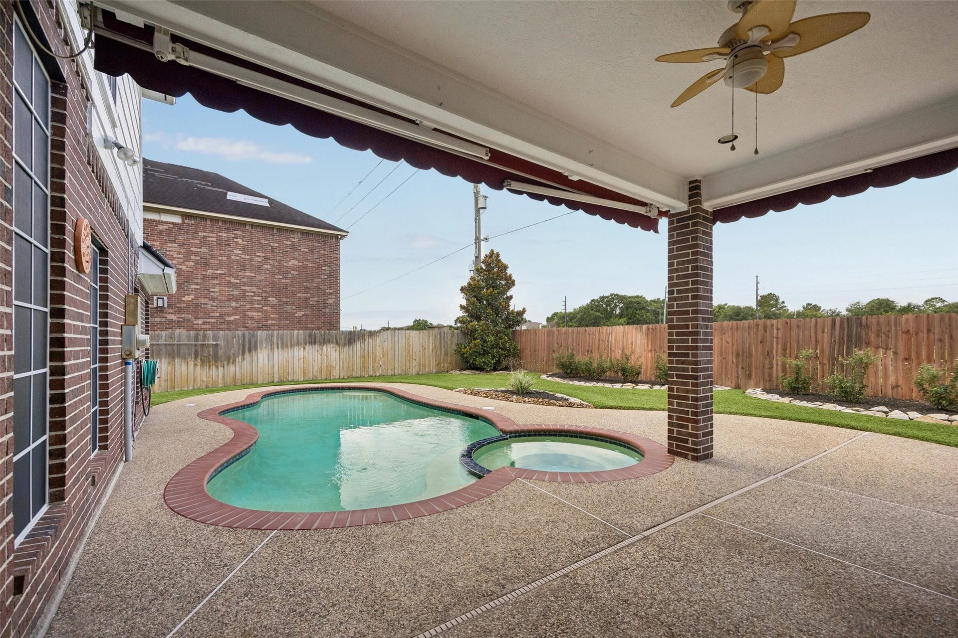 Charming backyard oasis featuring a sparkling pool with a hot tub, surrounded by a spacious covered patio great for barbequing and family gatherings.