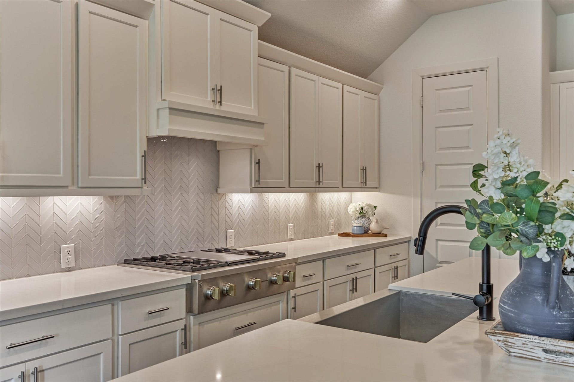 205 Patina Sorrel Drive, Montgomery, TX 77316 Elegant kitchen featuring a stylish herringbone backsplash. The spacious countertops and undermount sink provide functionality, complemented by under-cabinet lighting and tasteful decor.