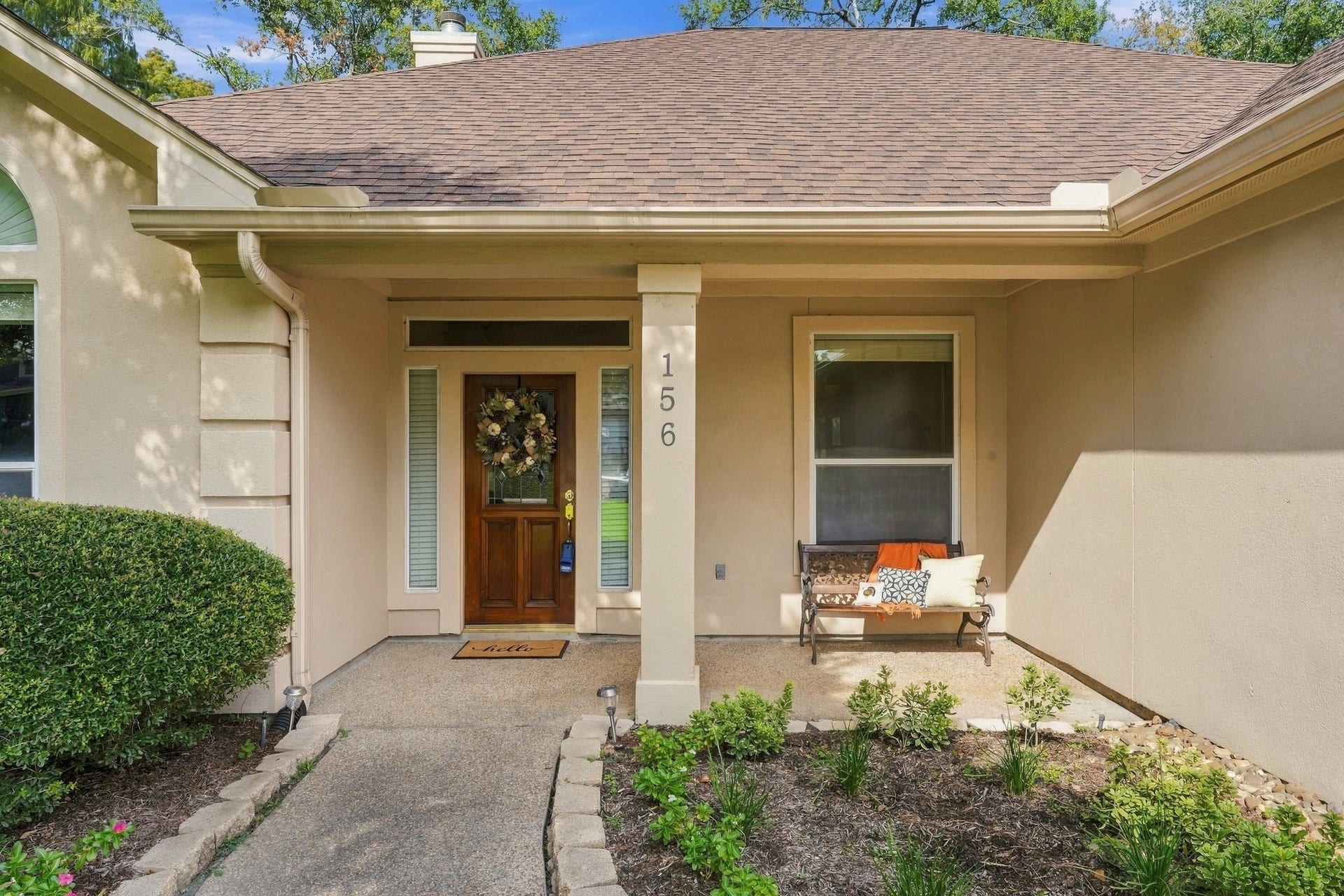 156 April Waters Drive W, Conroe, TX 77356 Charming single-story home with a spacious two-car garage, surrounded by lush greenery and mature trees.